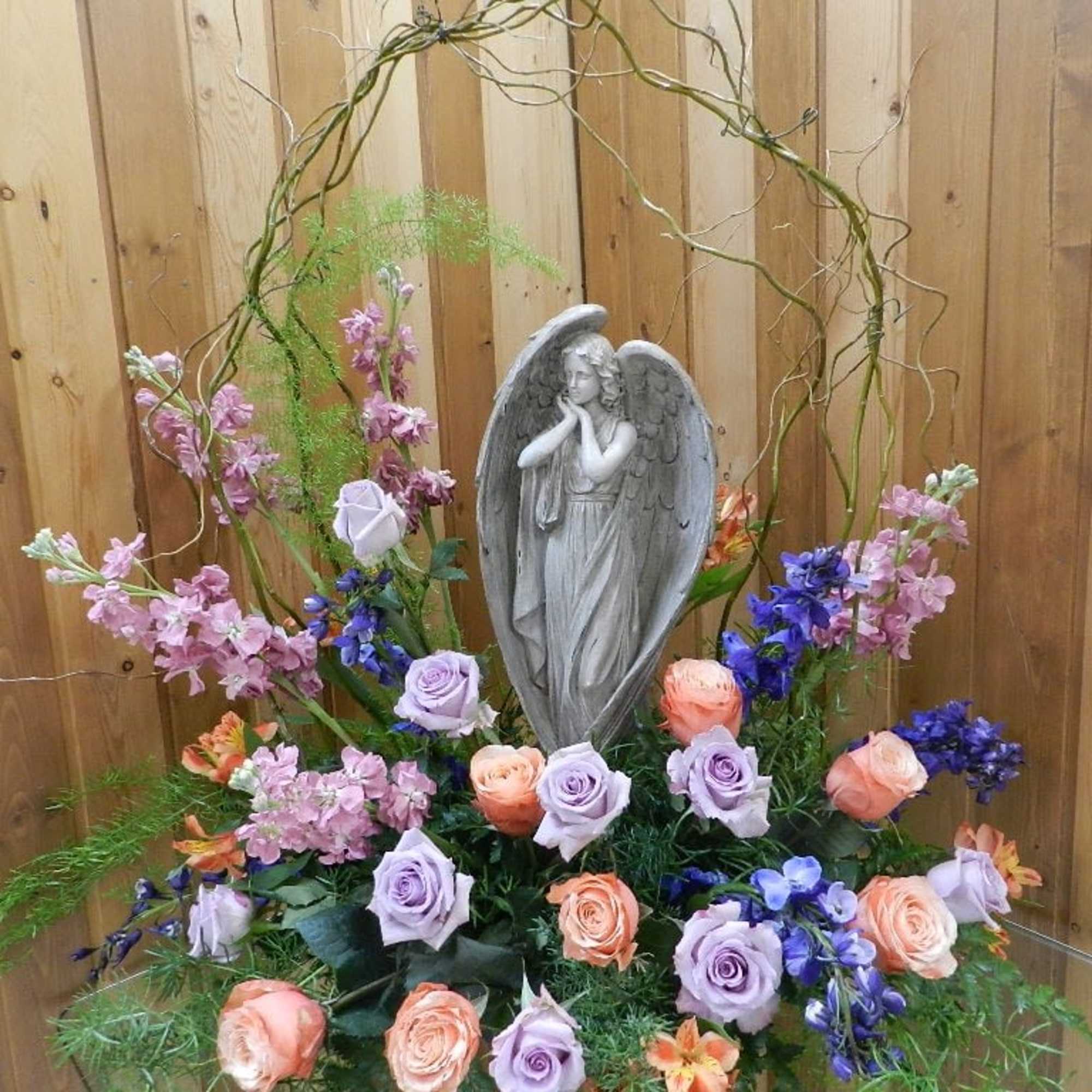 Floral arrangement with a gray angel statue and pastel roses