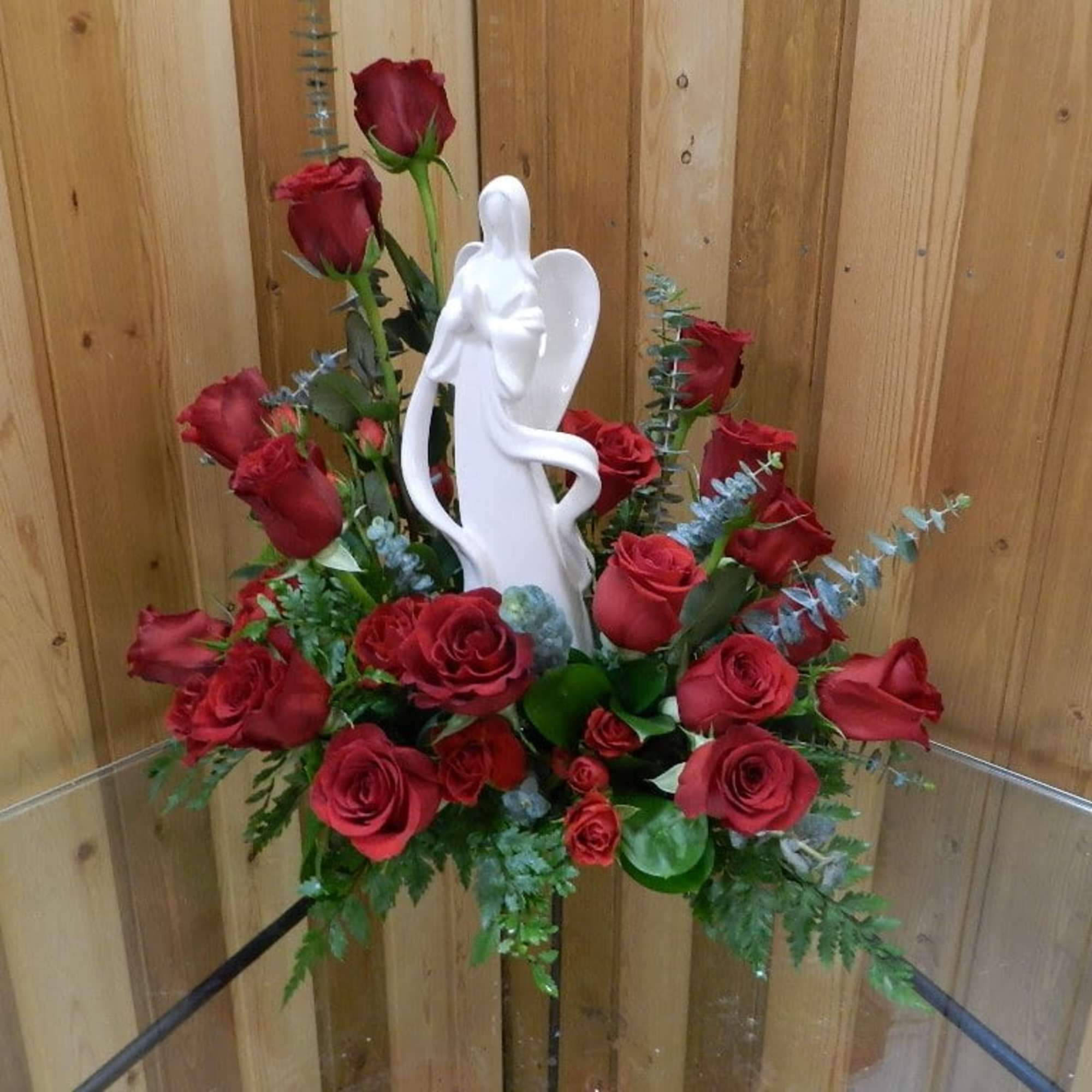 Red roses arranged around a white angel figurine
