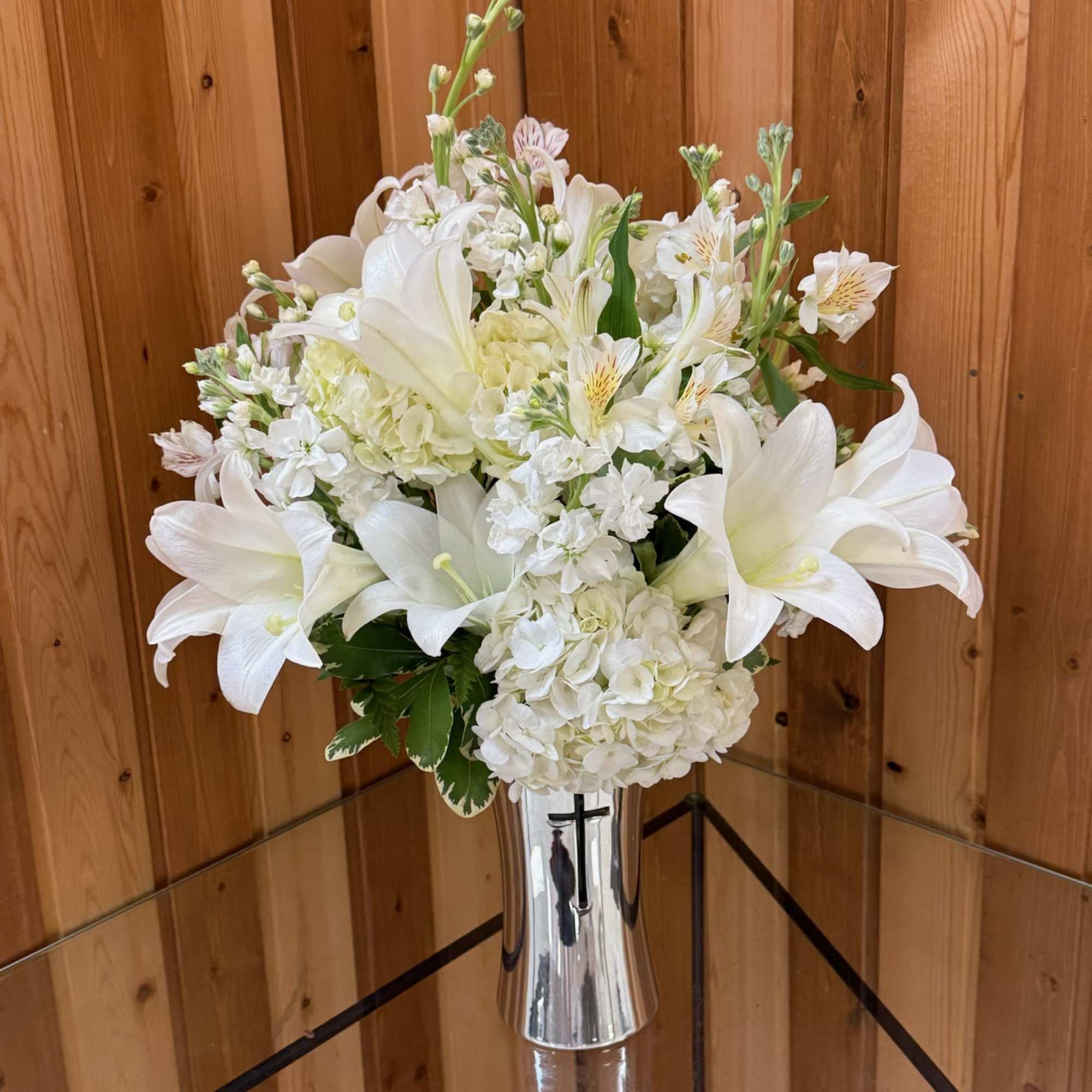 White floral arrangement in a silver vase with lilies and hydrangeas