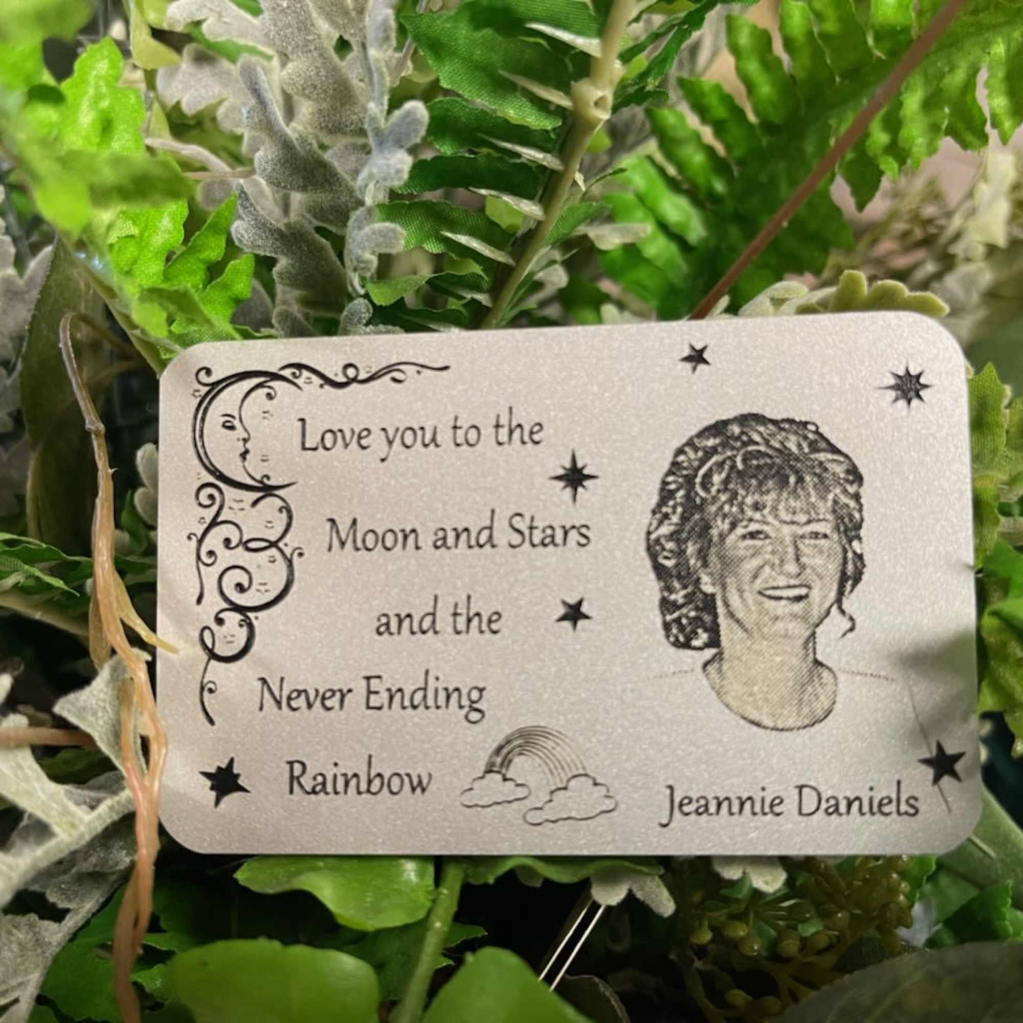 Artificial greenery with a memorial card reading "Love you to the Moon and Stars"