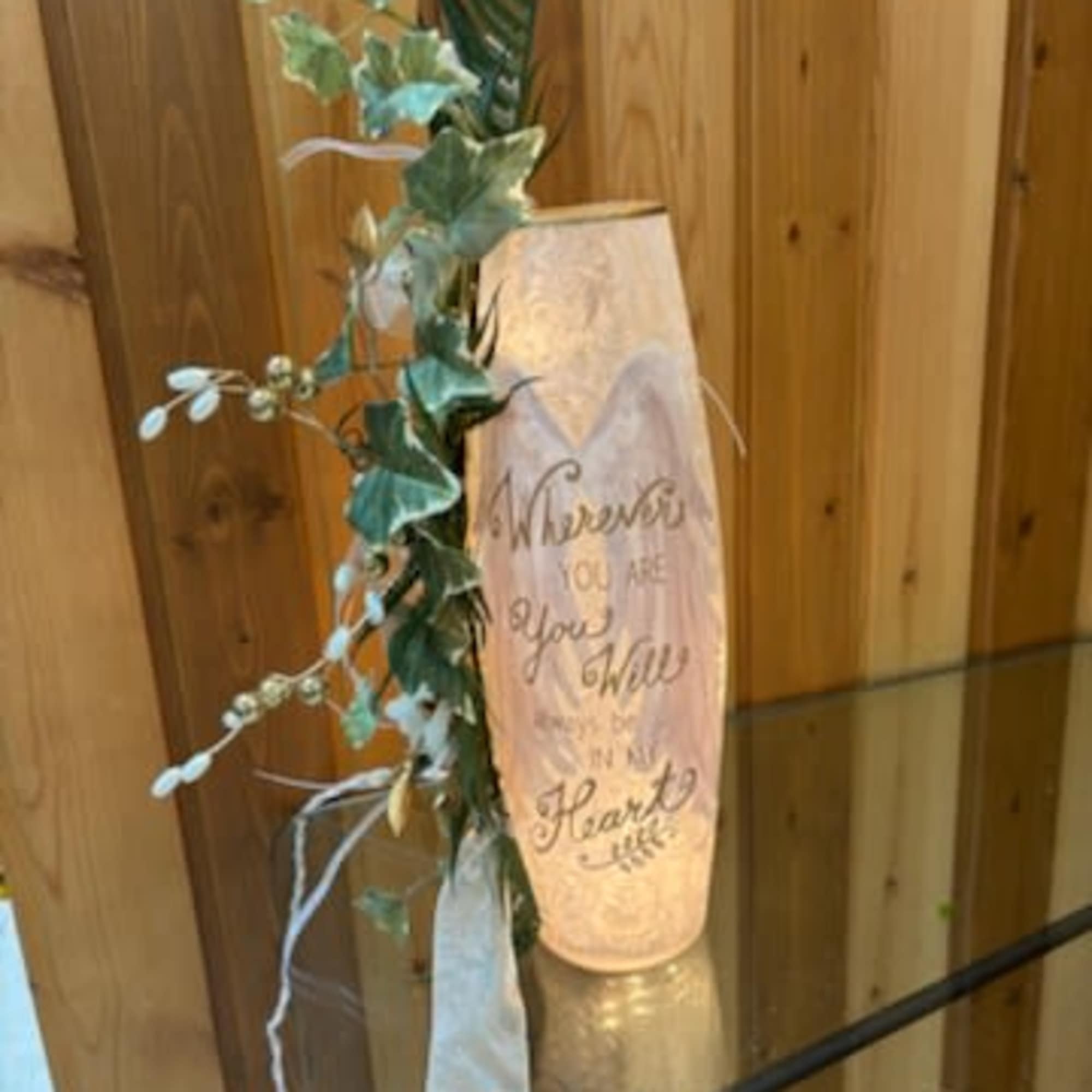 Decorative candle with ivy and ribbon beside a wooden wall