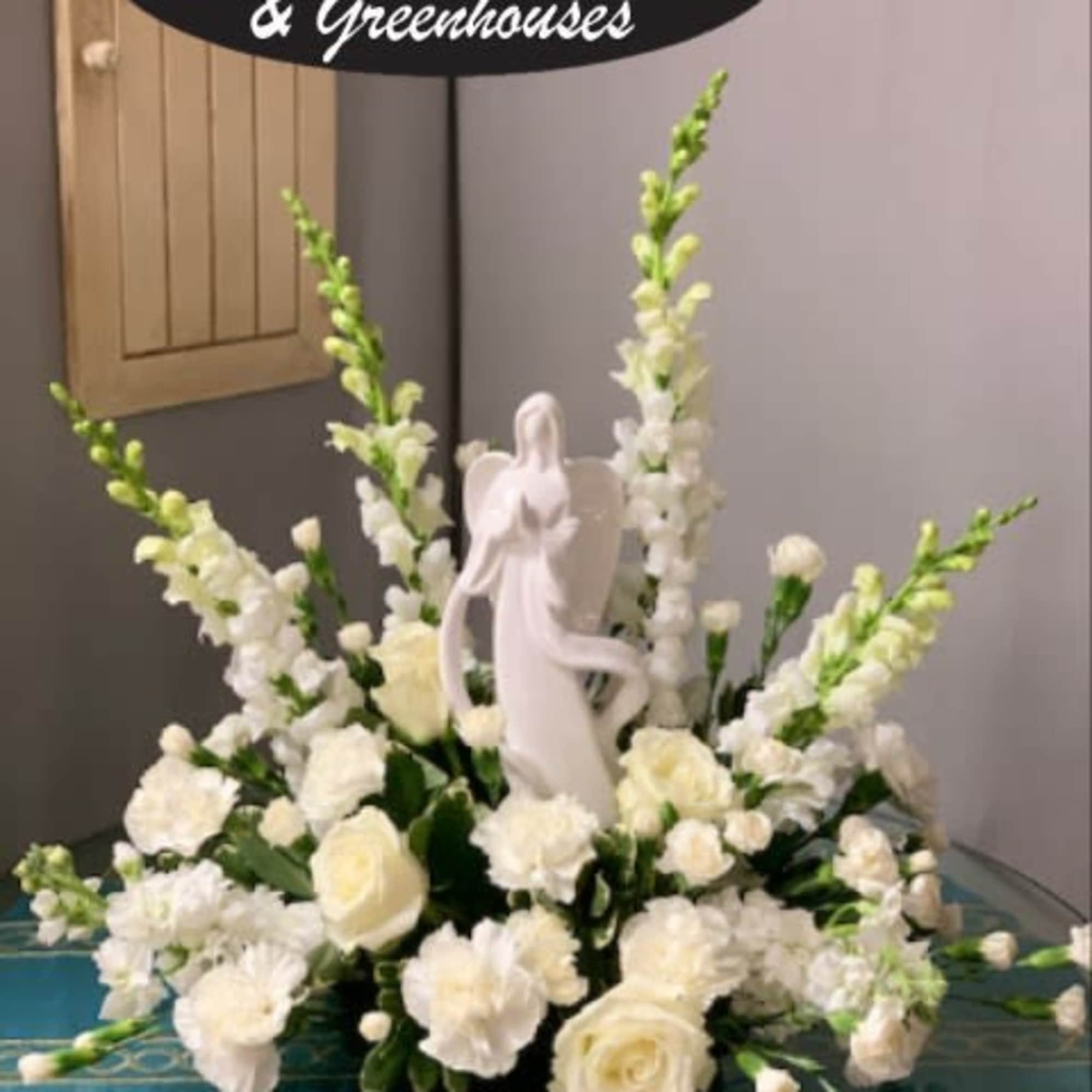 White floral arrangement with an angel figurine in the center
