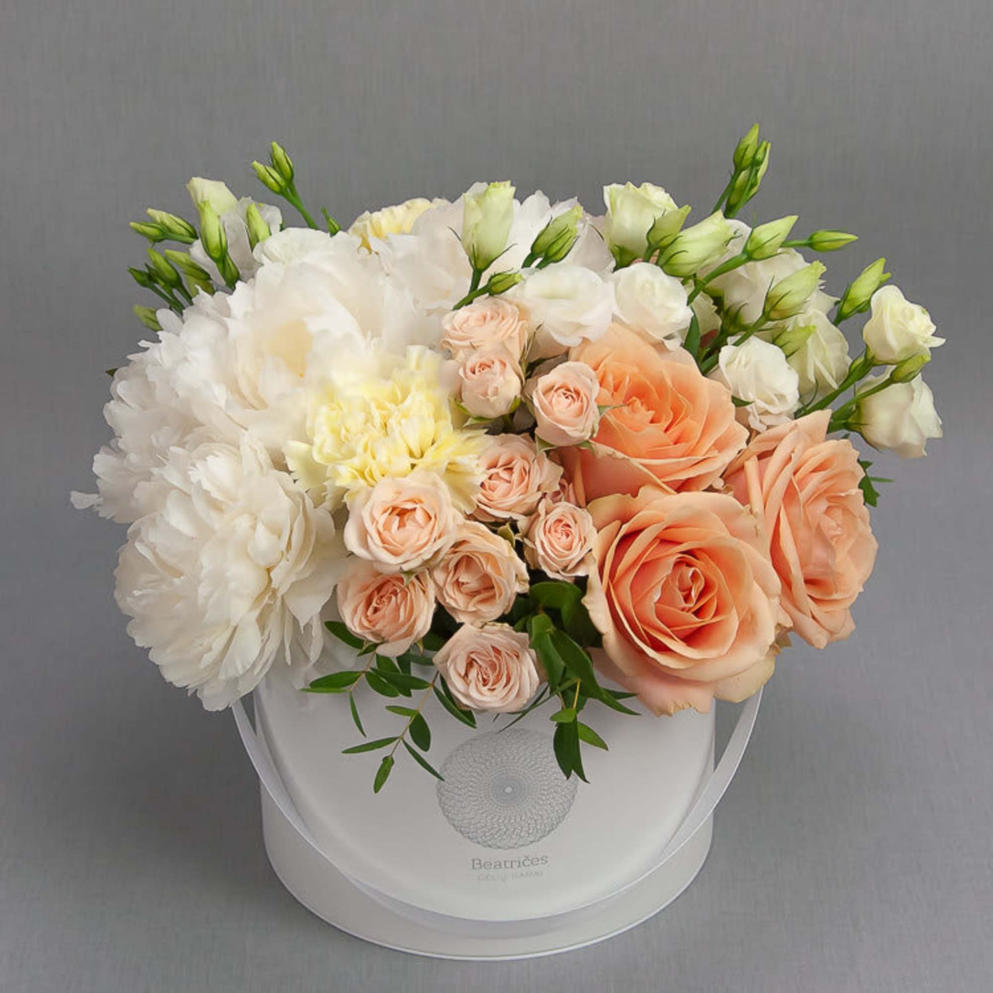 Peach roses and white blooms arranged in a white round box