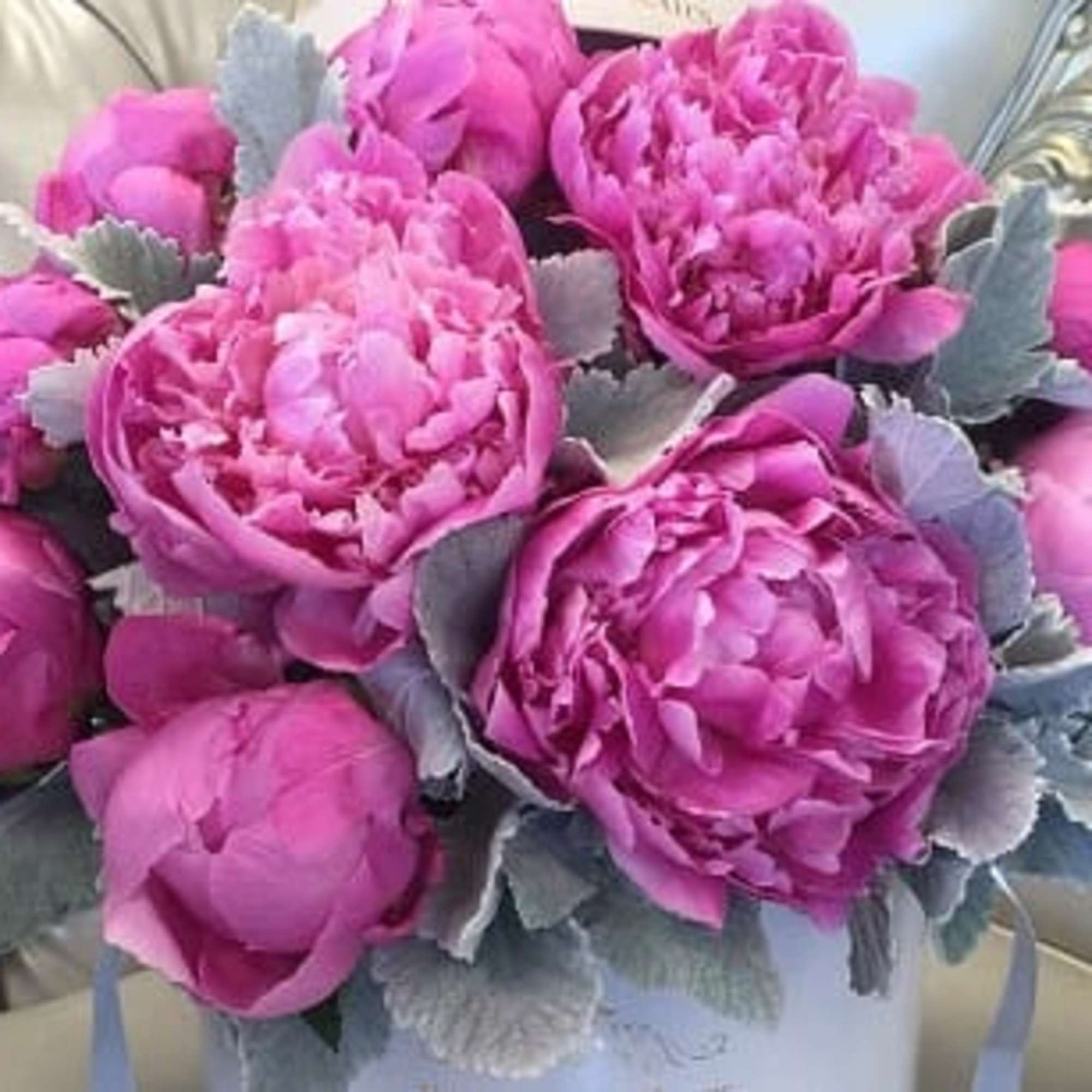 Pink peony bouquet with silvery foliage in a white container