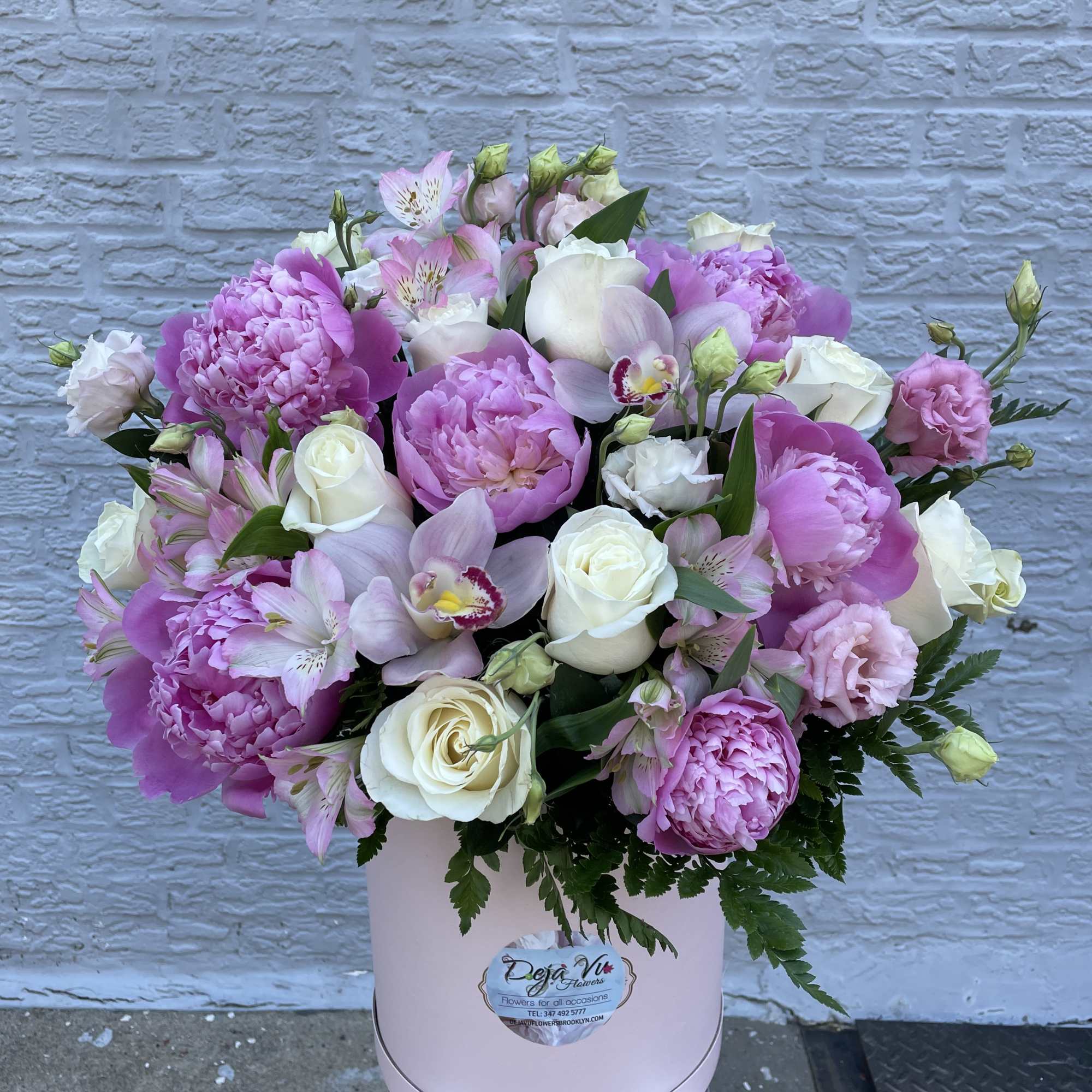 Pink and white mixed flower arrangement in a round box