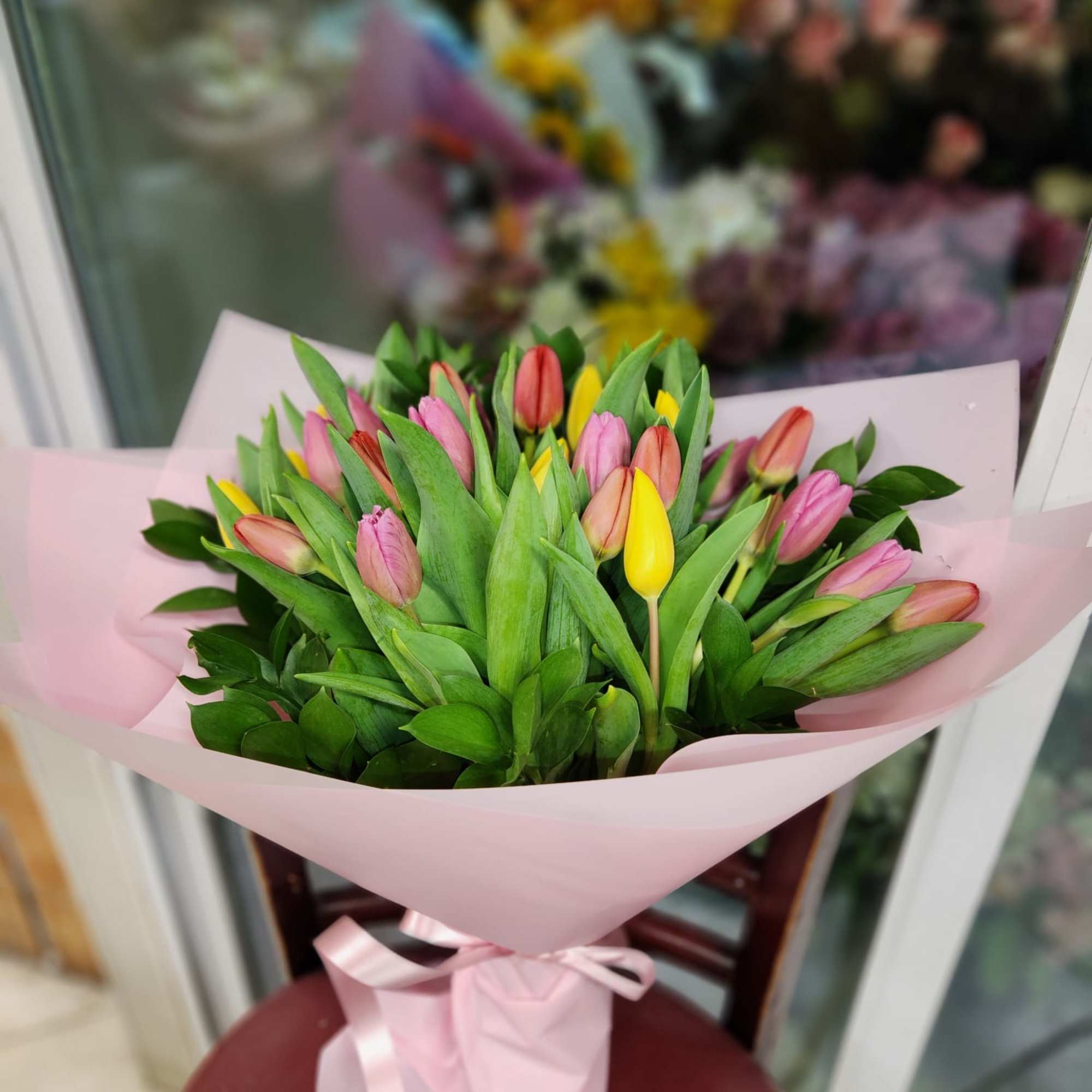 Bouquet of pink and yellow tulips wrapped in pale pink paper