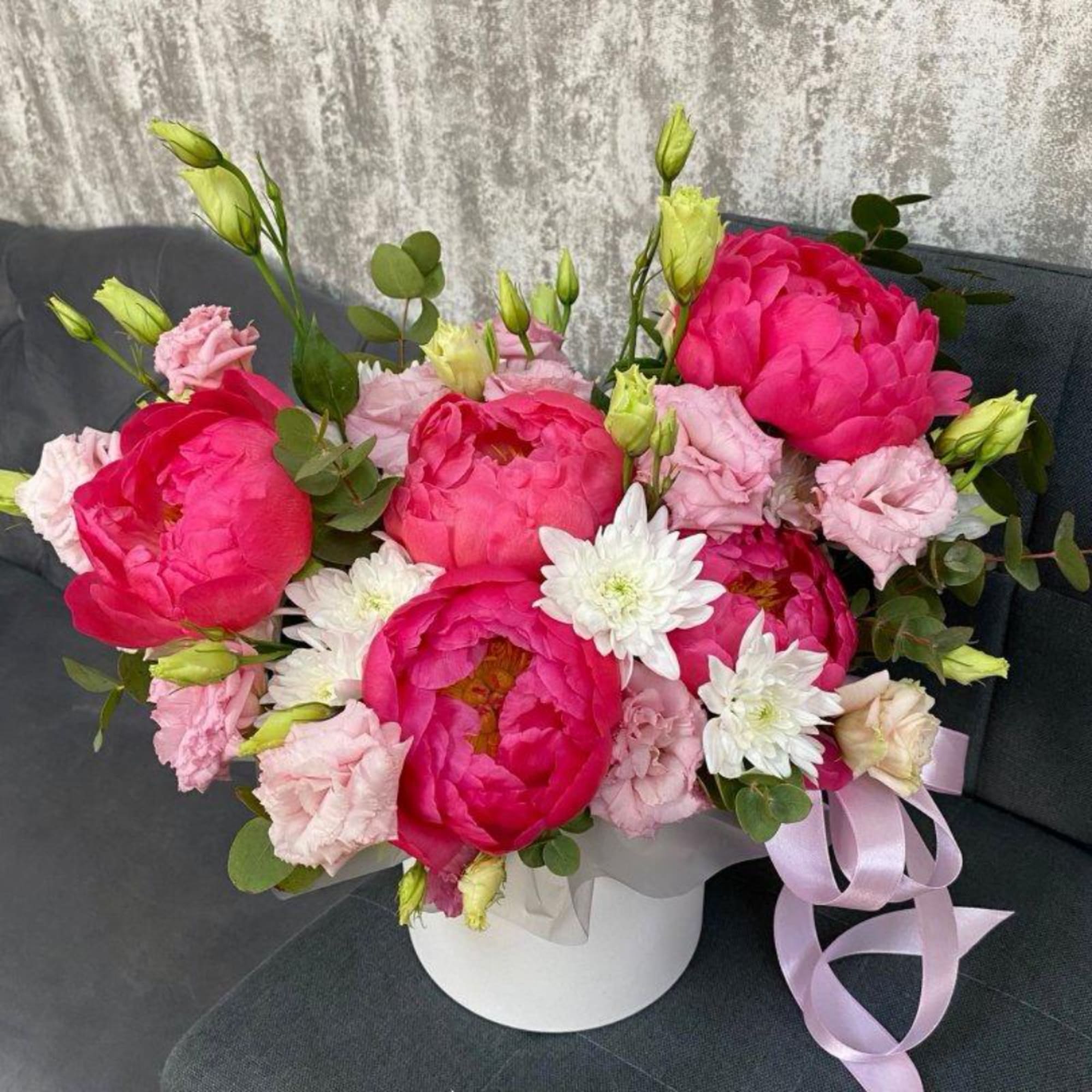Pink peonies and white daisies in a white hatbox with a ribbon