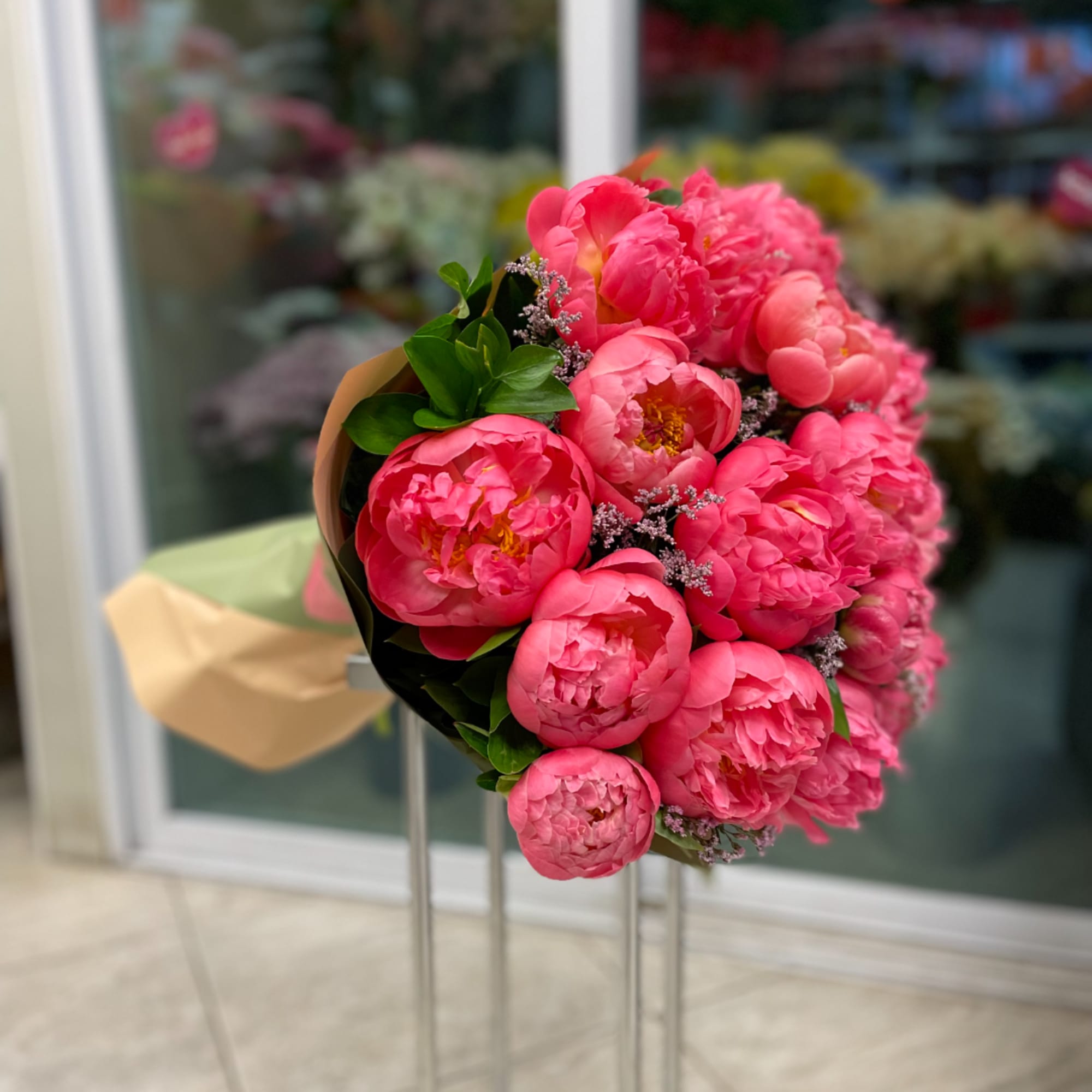 Bouquet of bright pink peonies with greenery and small filler flowers