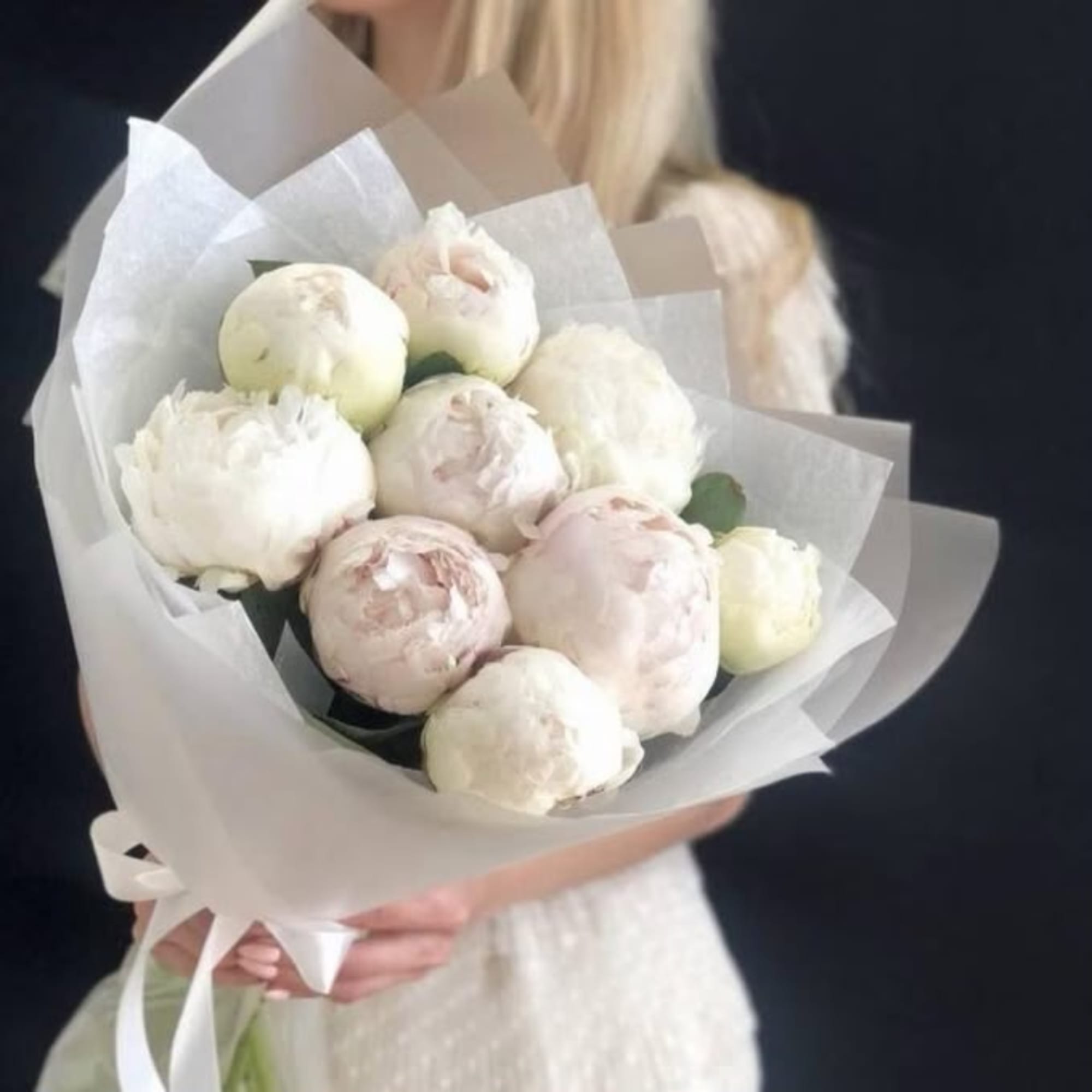 Bouquet of white peonies wrapped in translucent paper