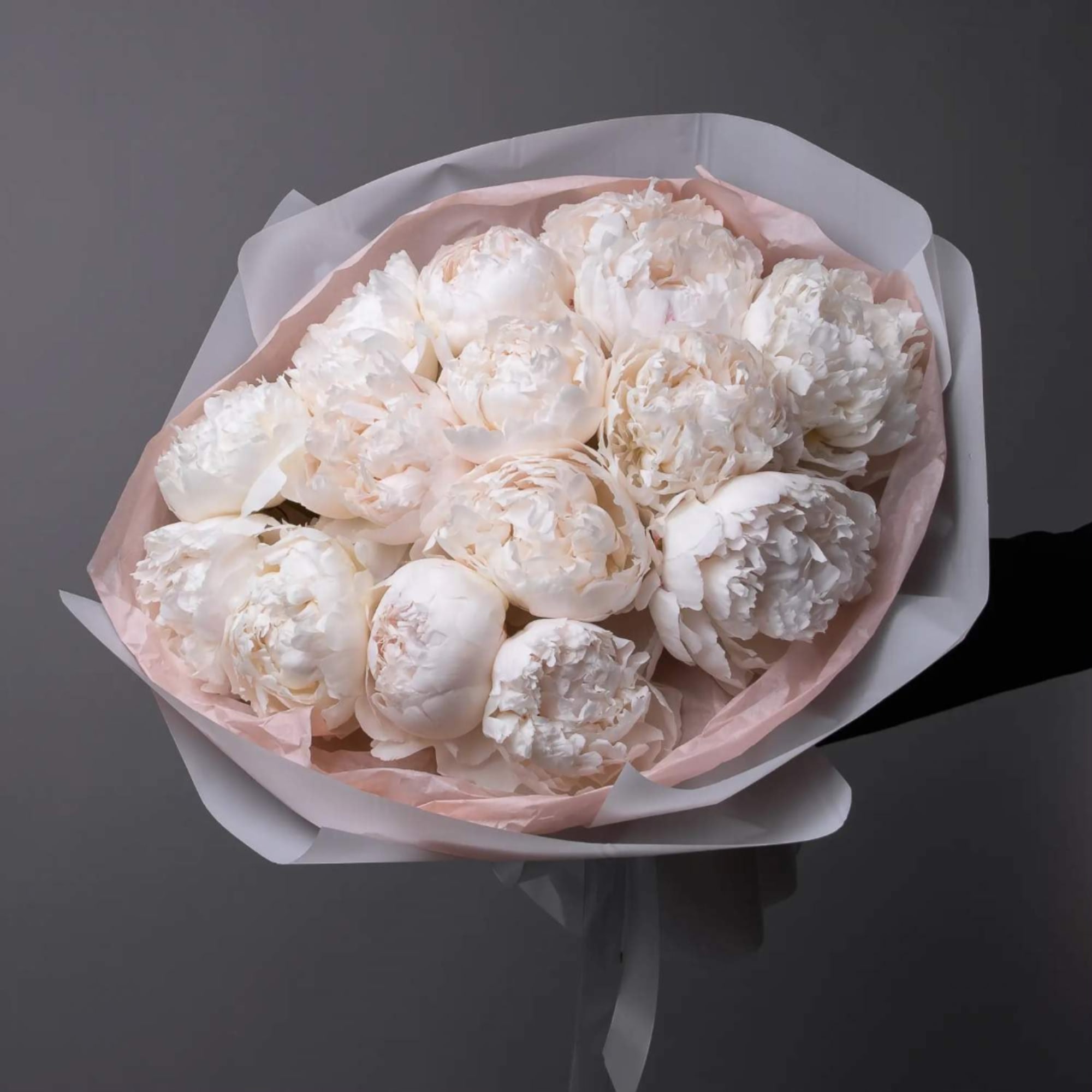 Bouquet of white peonies wrapped in pale pink paper
