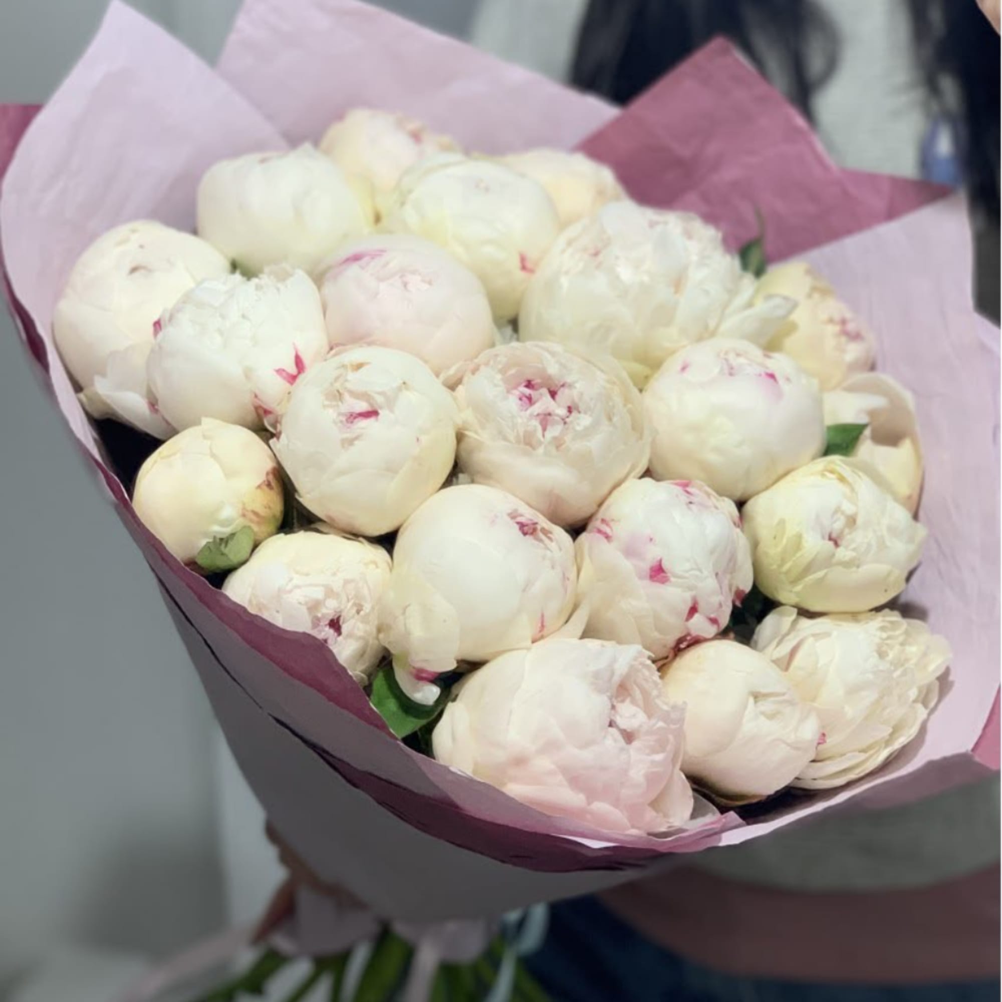 Bouquet of pale pink and white peonies wrapped in pink paper