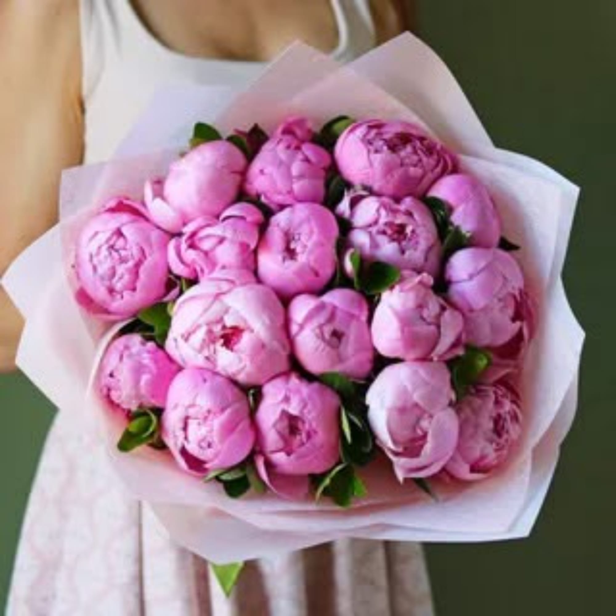 Bouquet of pink peonies wrapped in pale paper