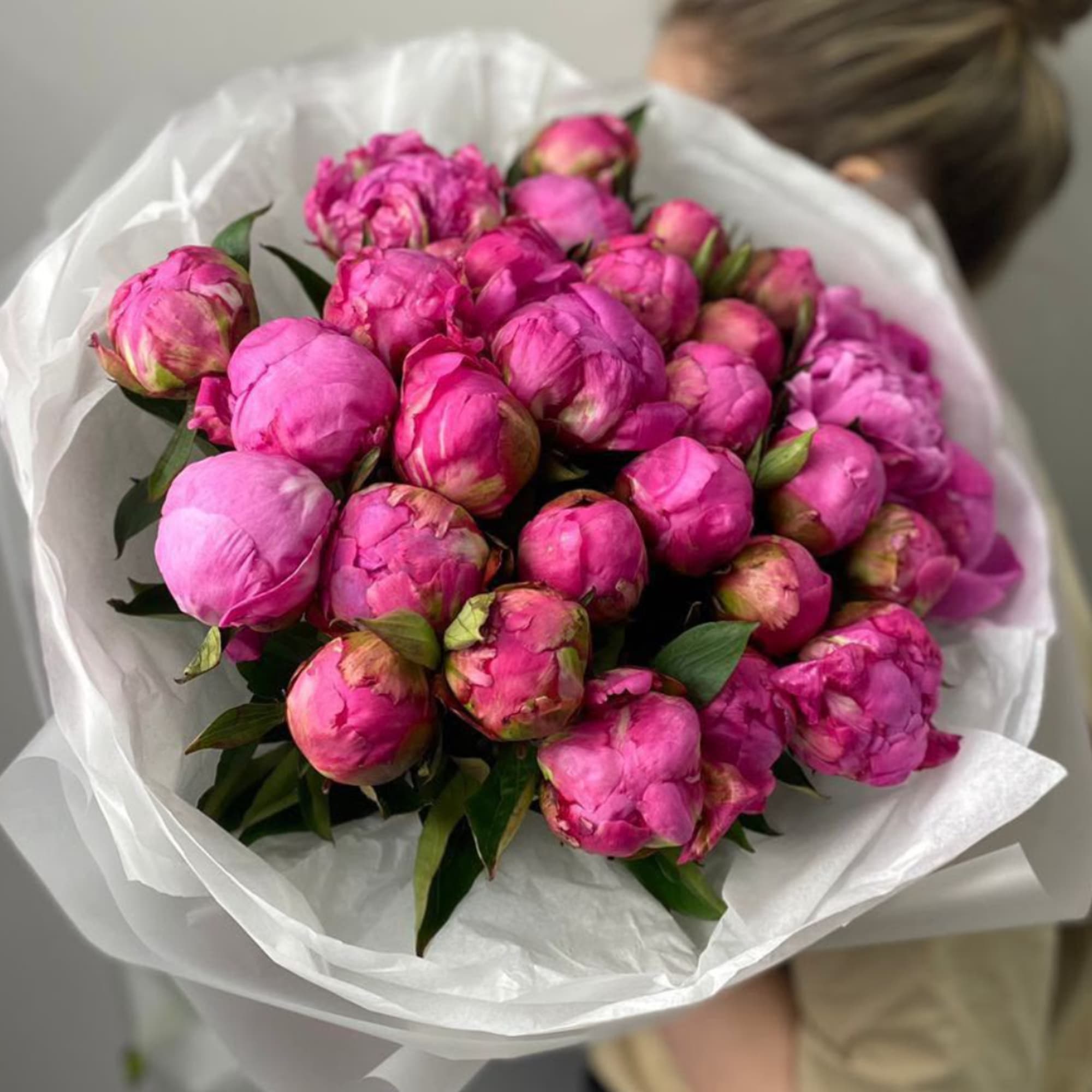 Bouquet of bright pink peonies wrapped in white paper