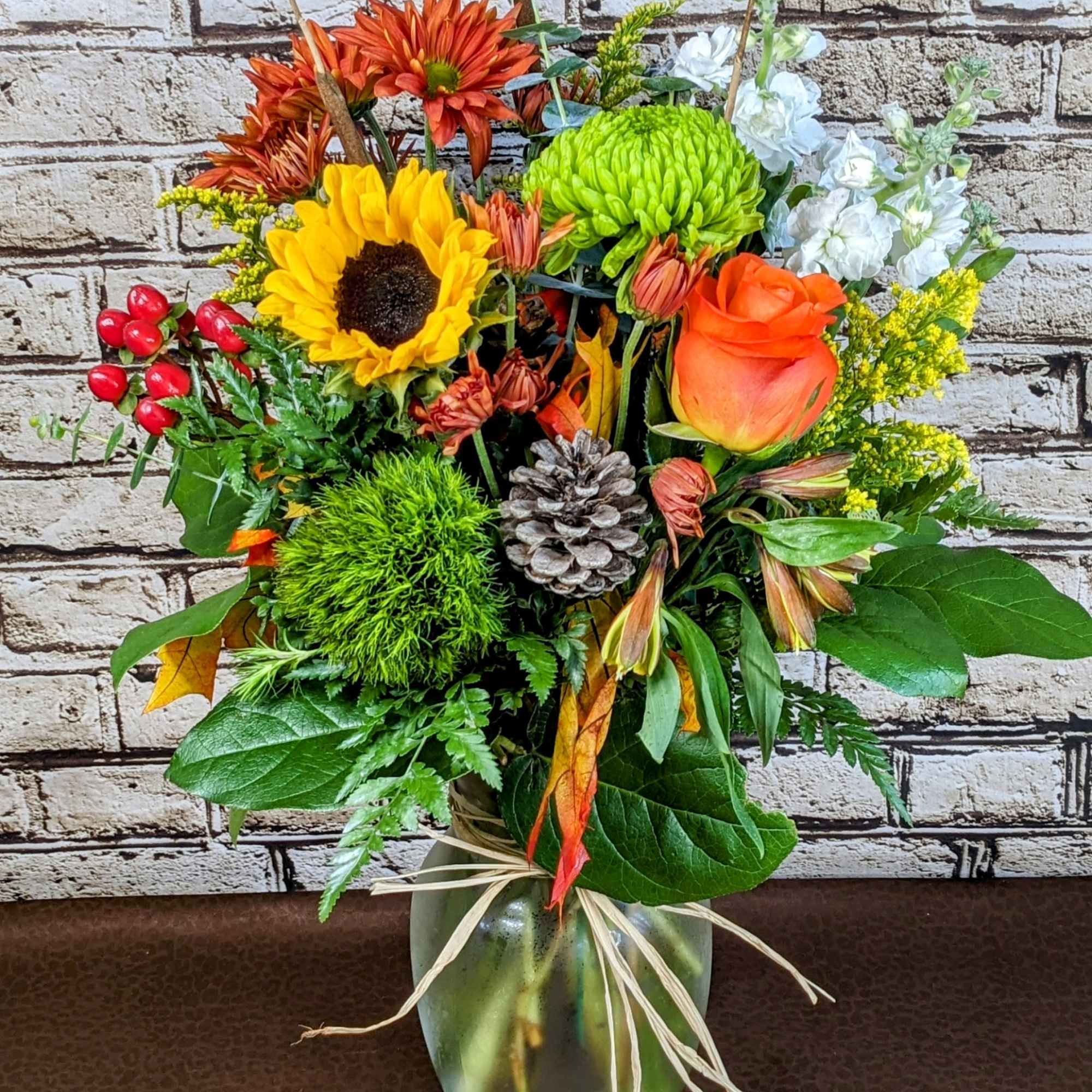 Mixed bouquet in a glass vase with sunflowers, roses, and chrysanthemums