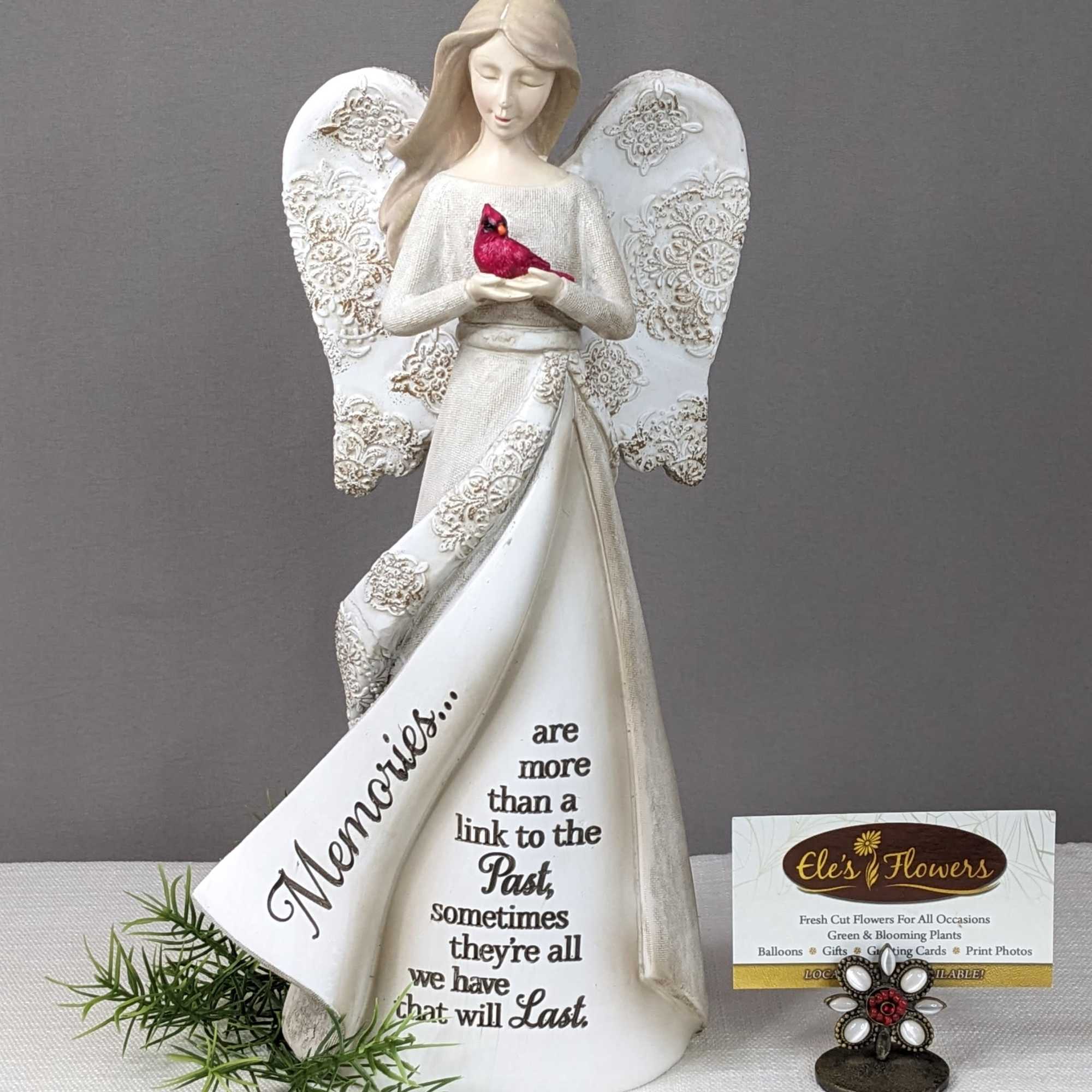 Decorative angel figurine holding a red bird with a memorial message on the dress