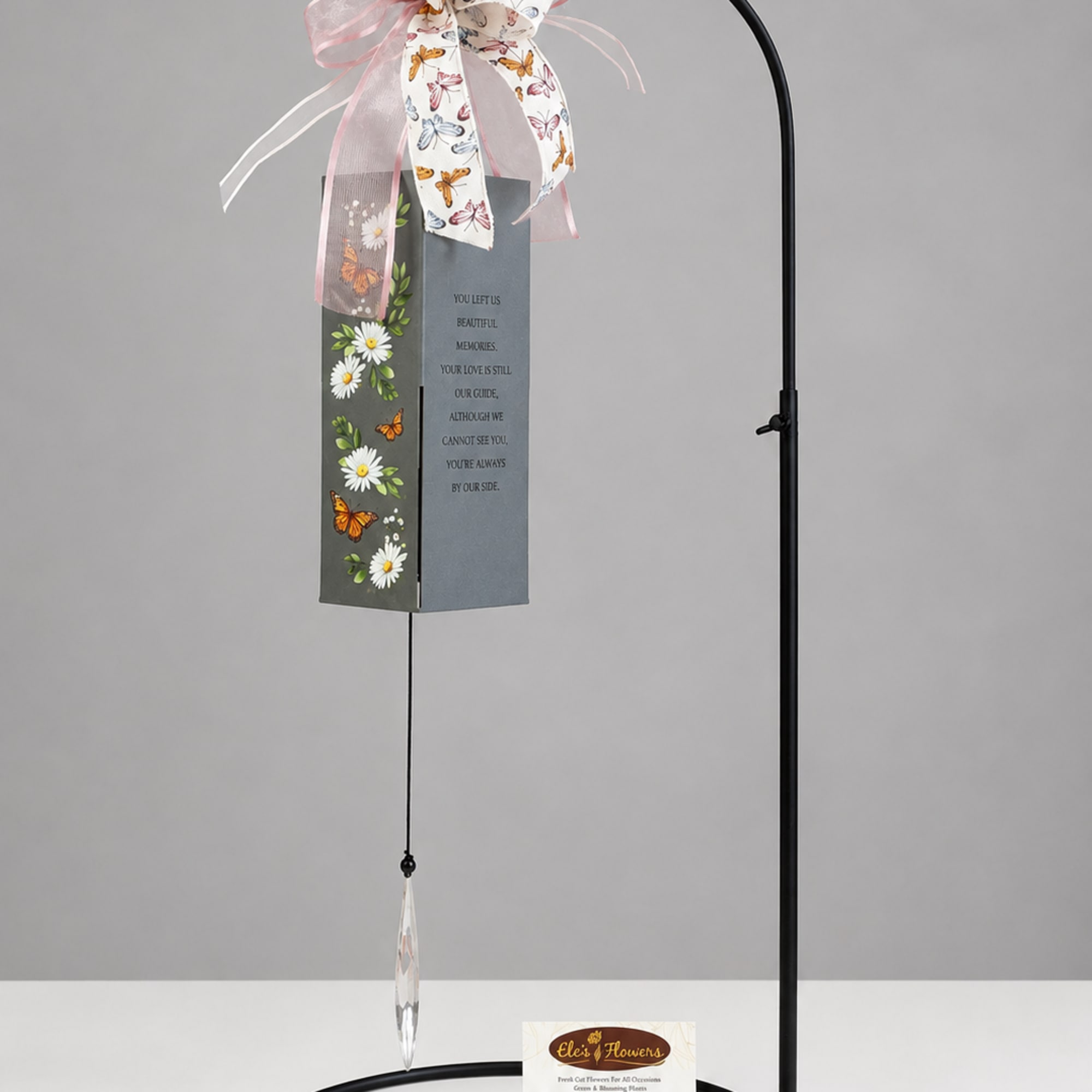 Memorial wind chime with butterfly and daisy decoration hanging from a black stand