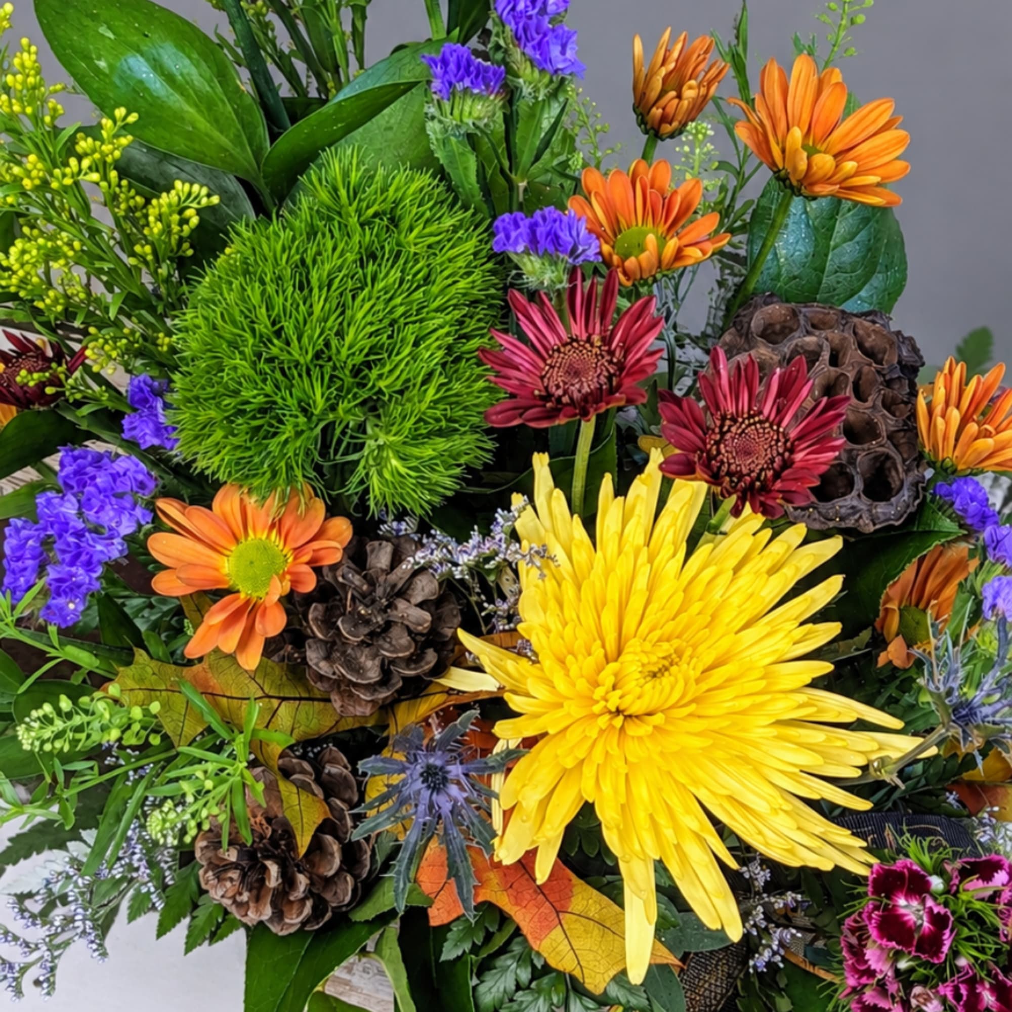 Mixed bouquet with yellow, orange, and purple flowers and pinecones
