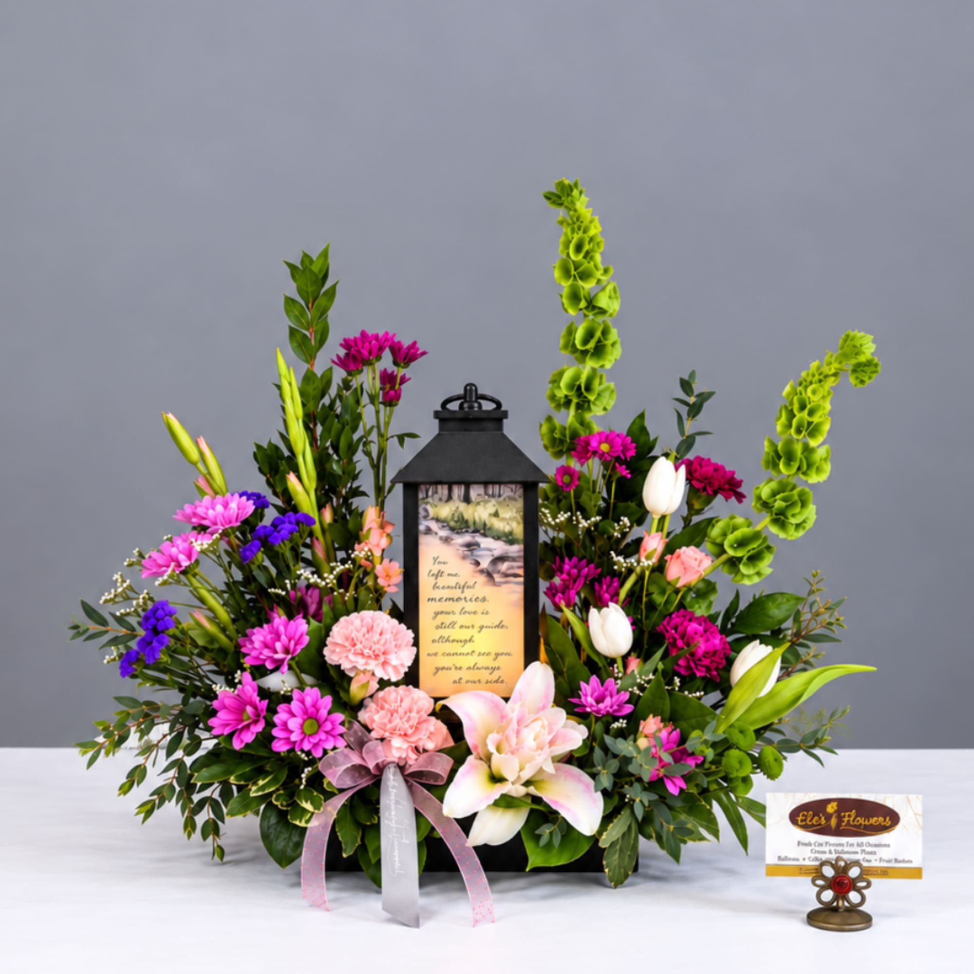 Mixed floral arrangement with a lantern centerpiece and ribbon bow