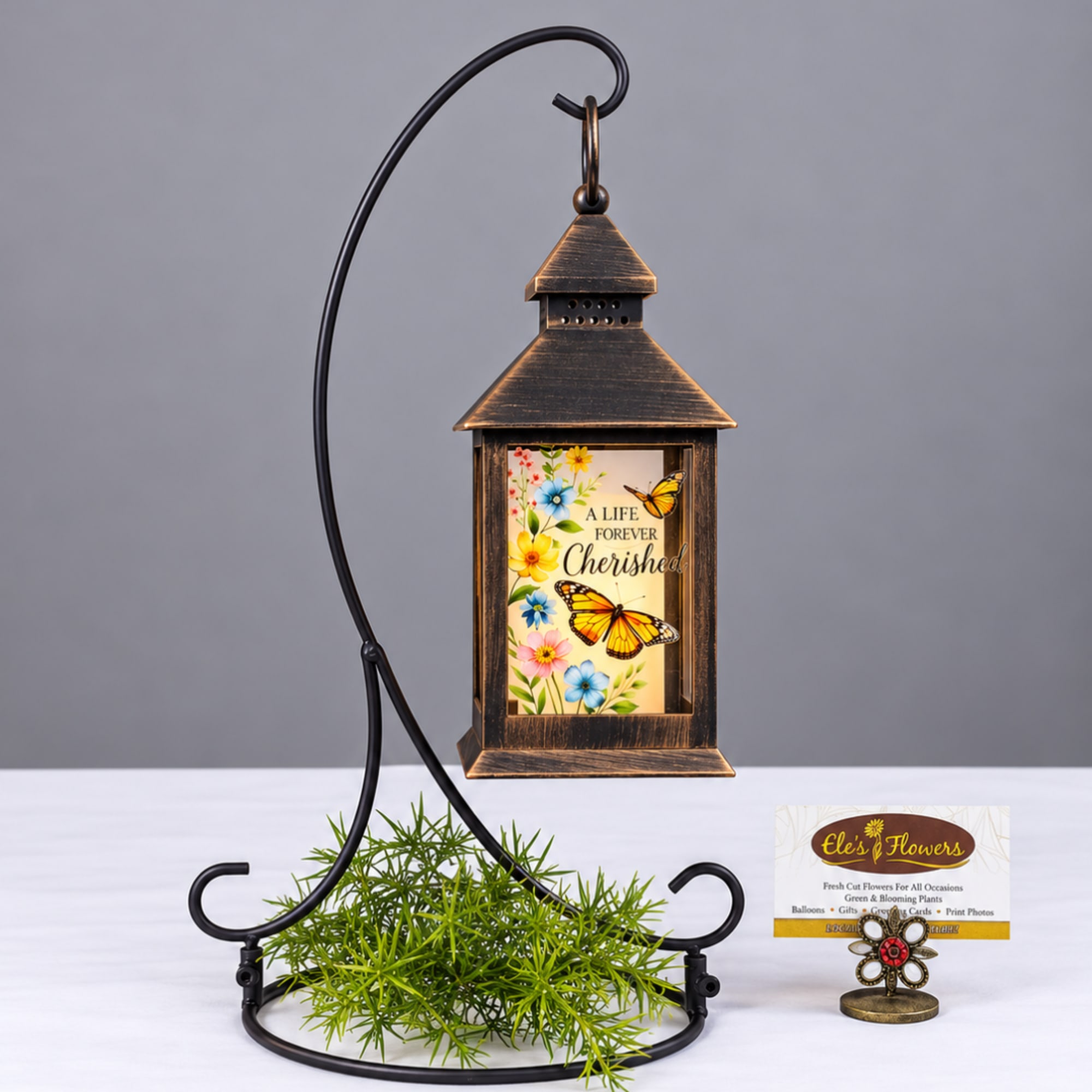Decorative lantern with a floral butterfly insert on a metal stand
