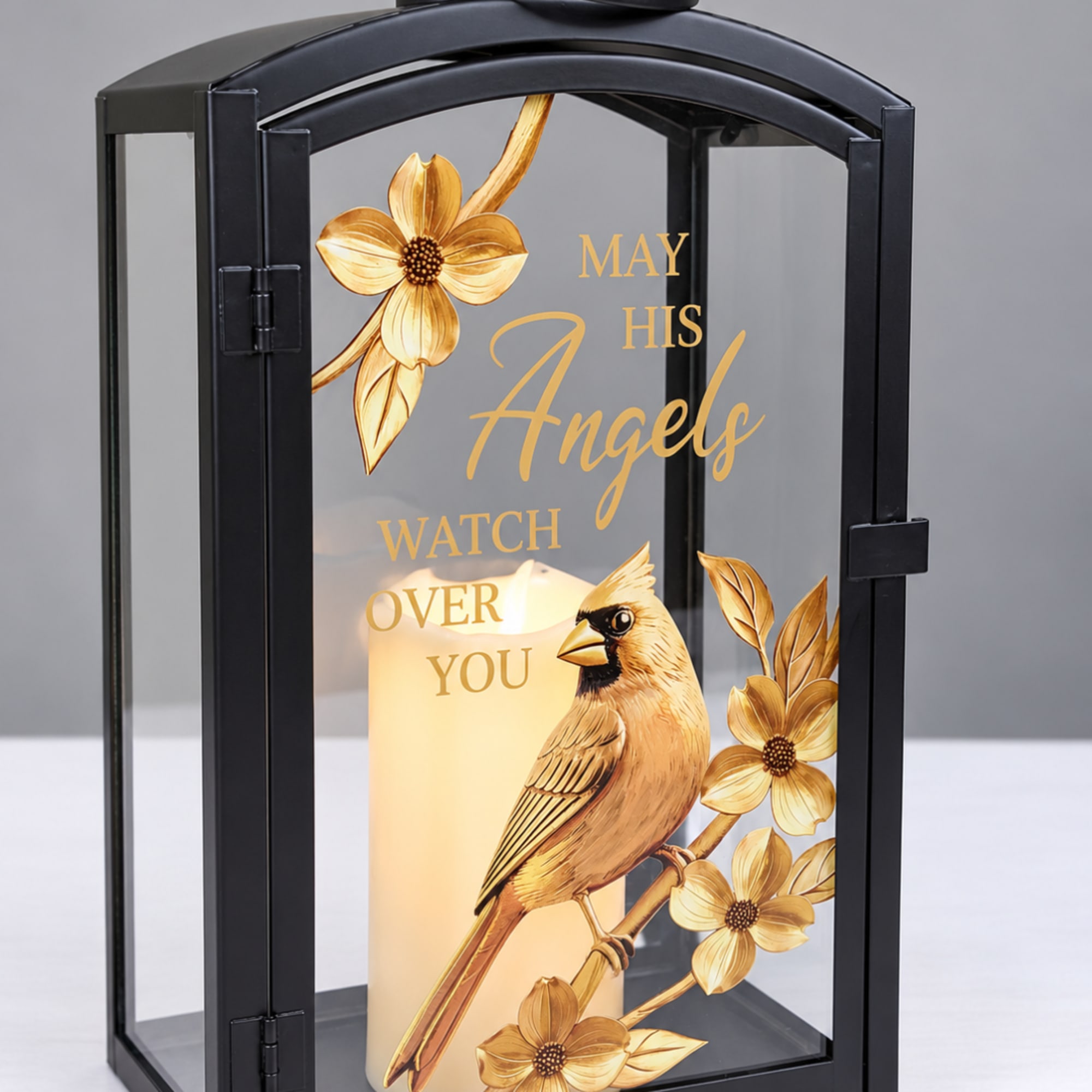 Black lantern with a lit candle and gold cardinal and floral design