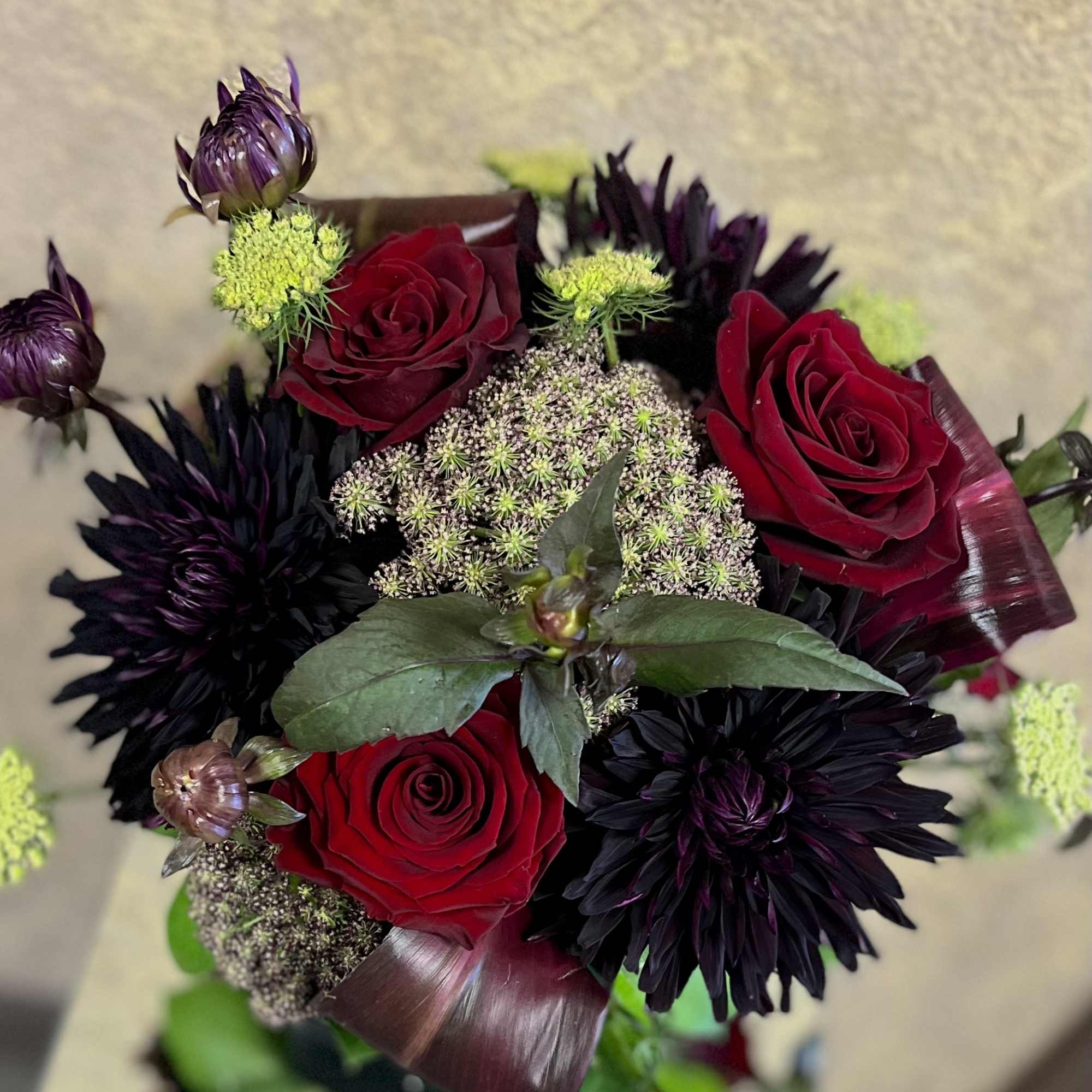 Bouquet of red roses and dark purple flowers with green accents