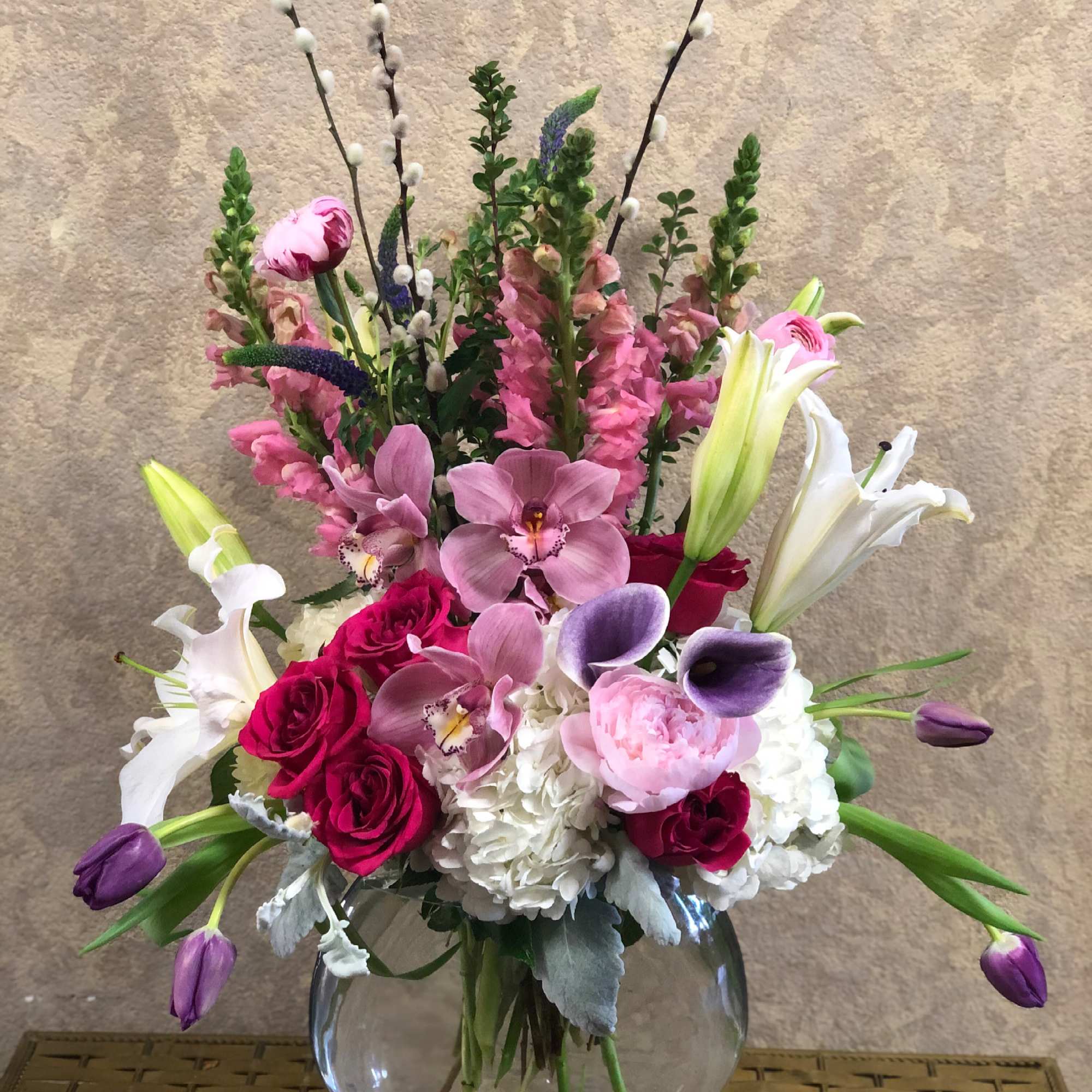 Mixed bouquet in a round glass vase with pink, white, and purple flowers