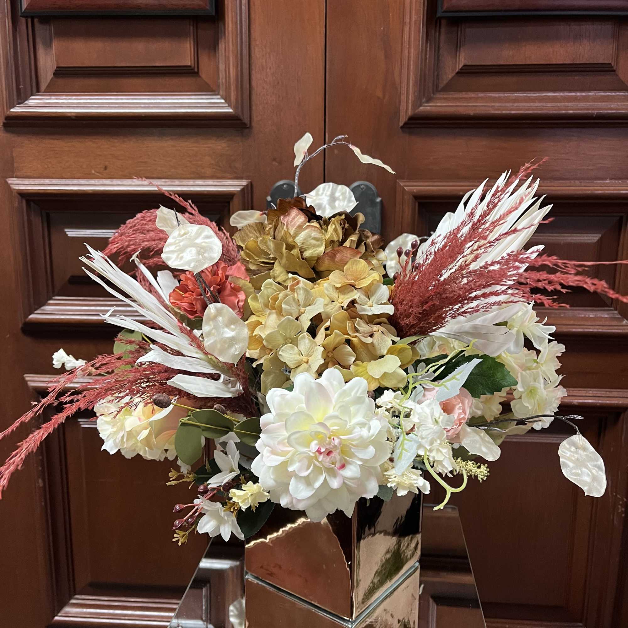 Arrangement of cream and blush flowers in a mirrored vase