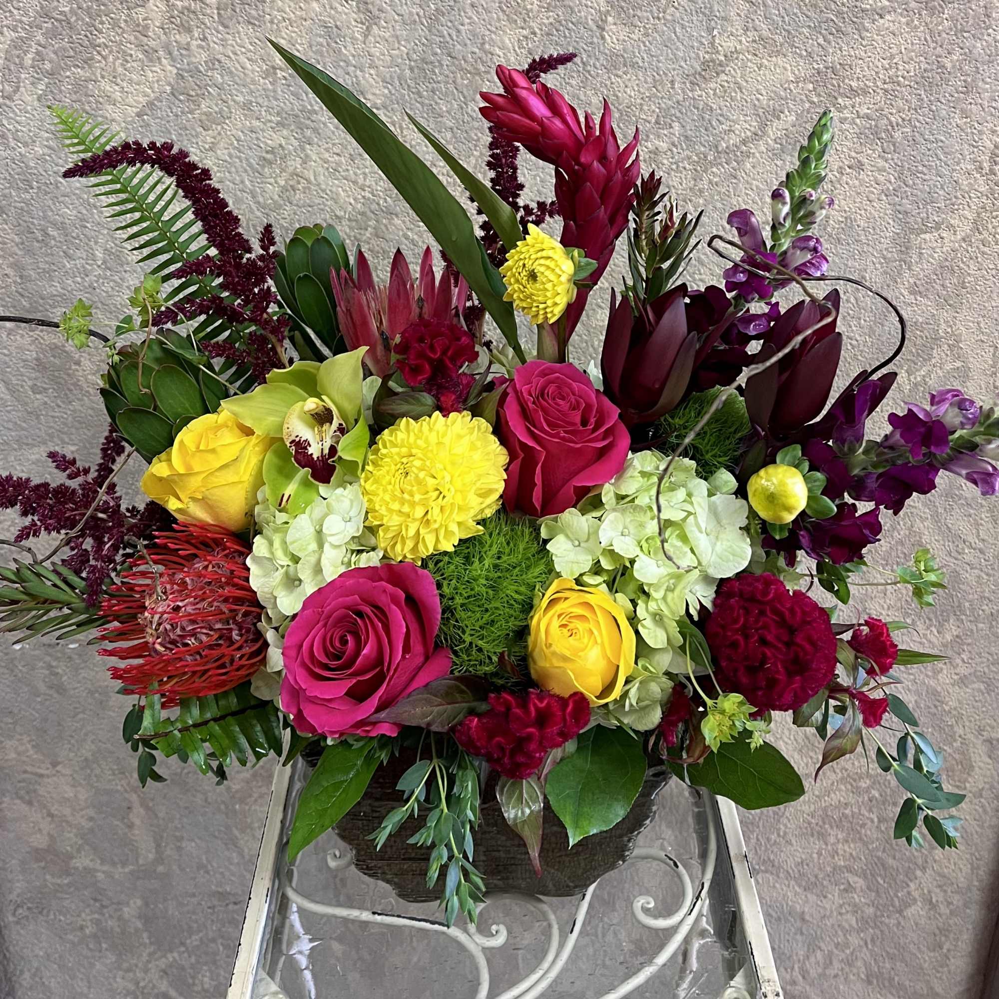 Colorful mixed flower arrangement in a vase with roses and orchids
