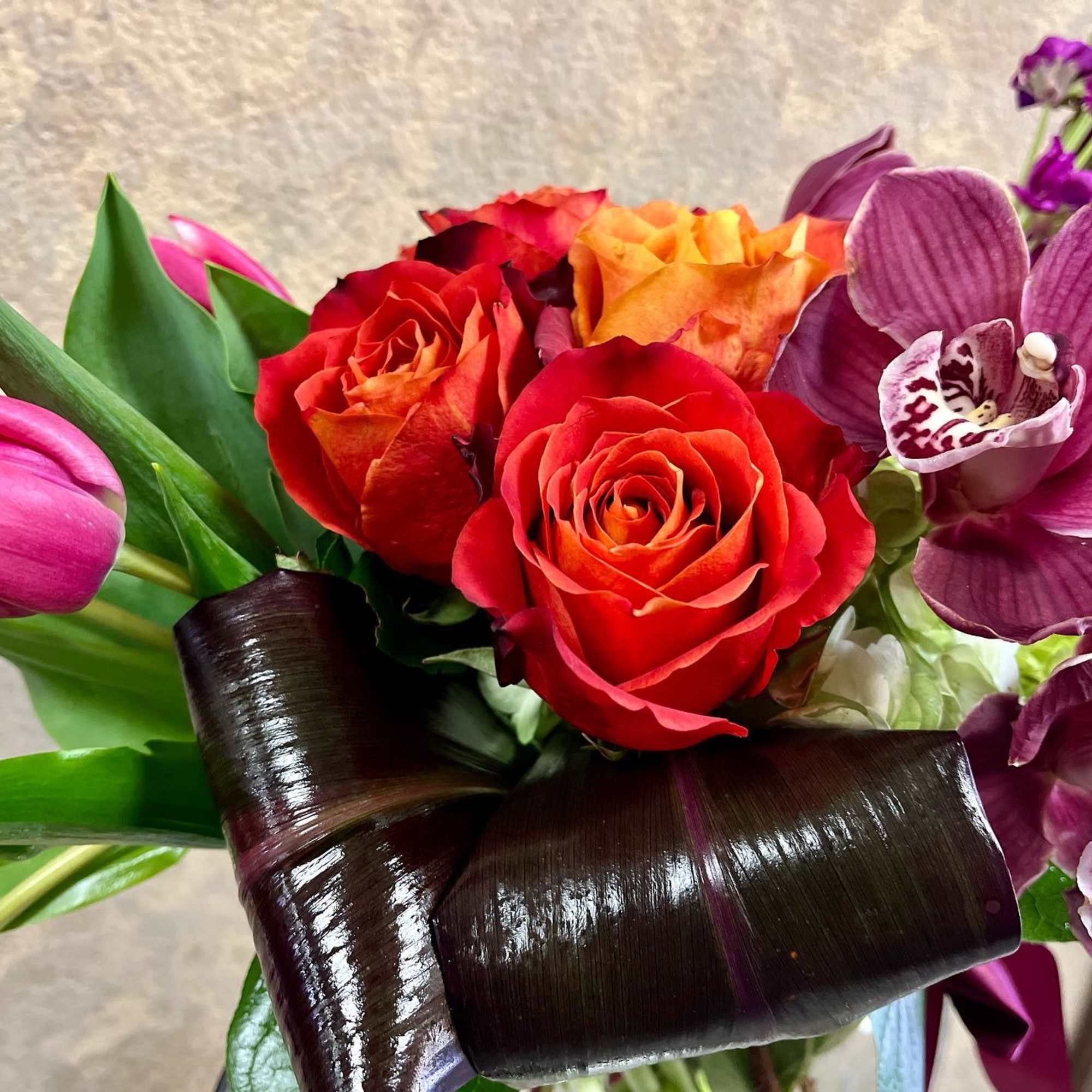 Bouquet of red and orange roses with purple orchids and pink tulips