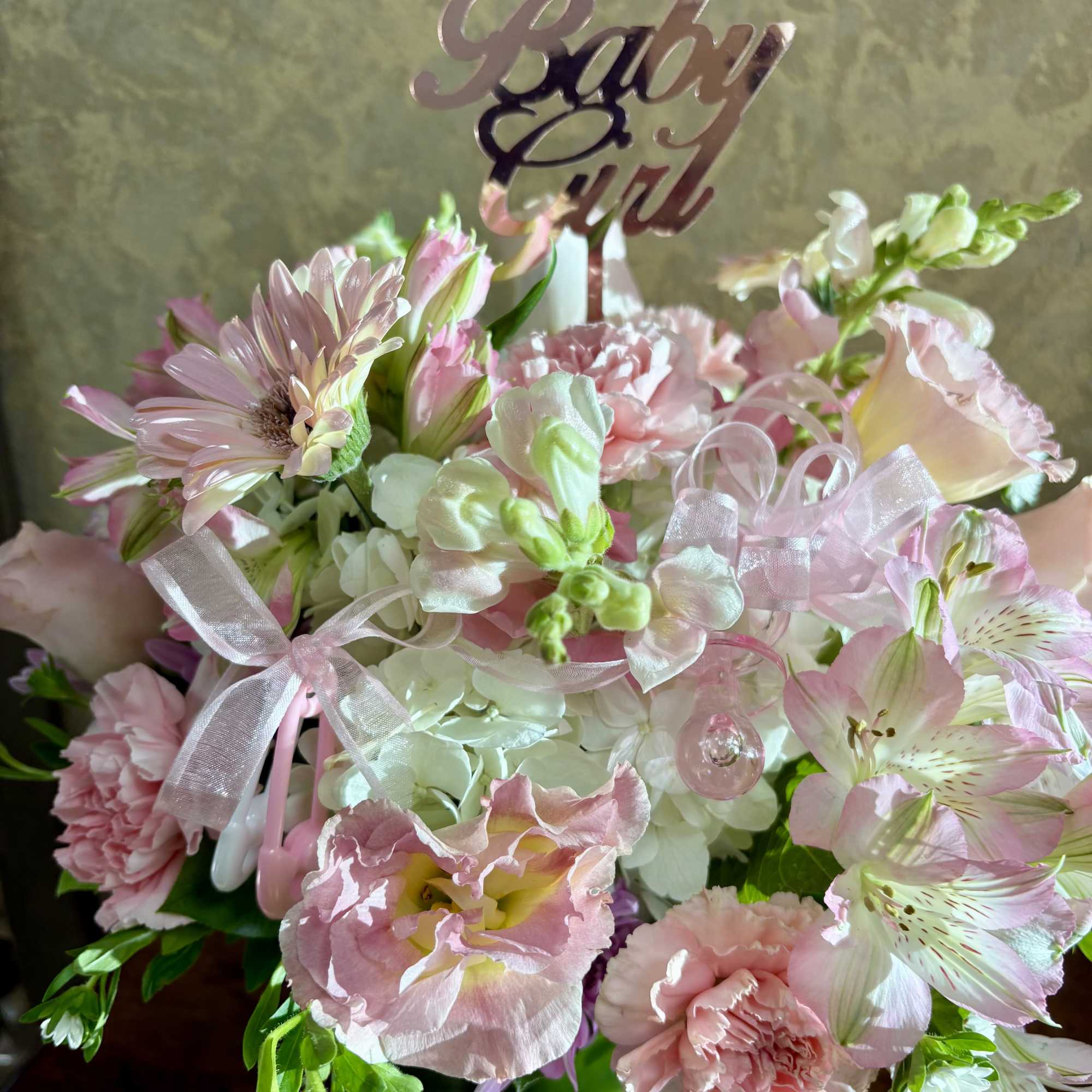 Pink and white floral arrangement with a "Baby Girl" topper in a green vase