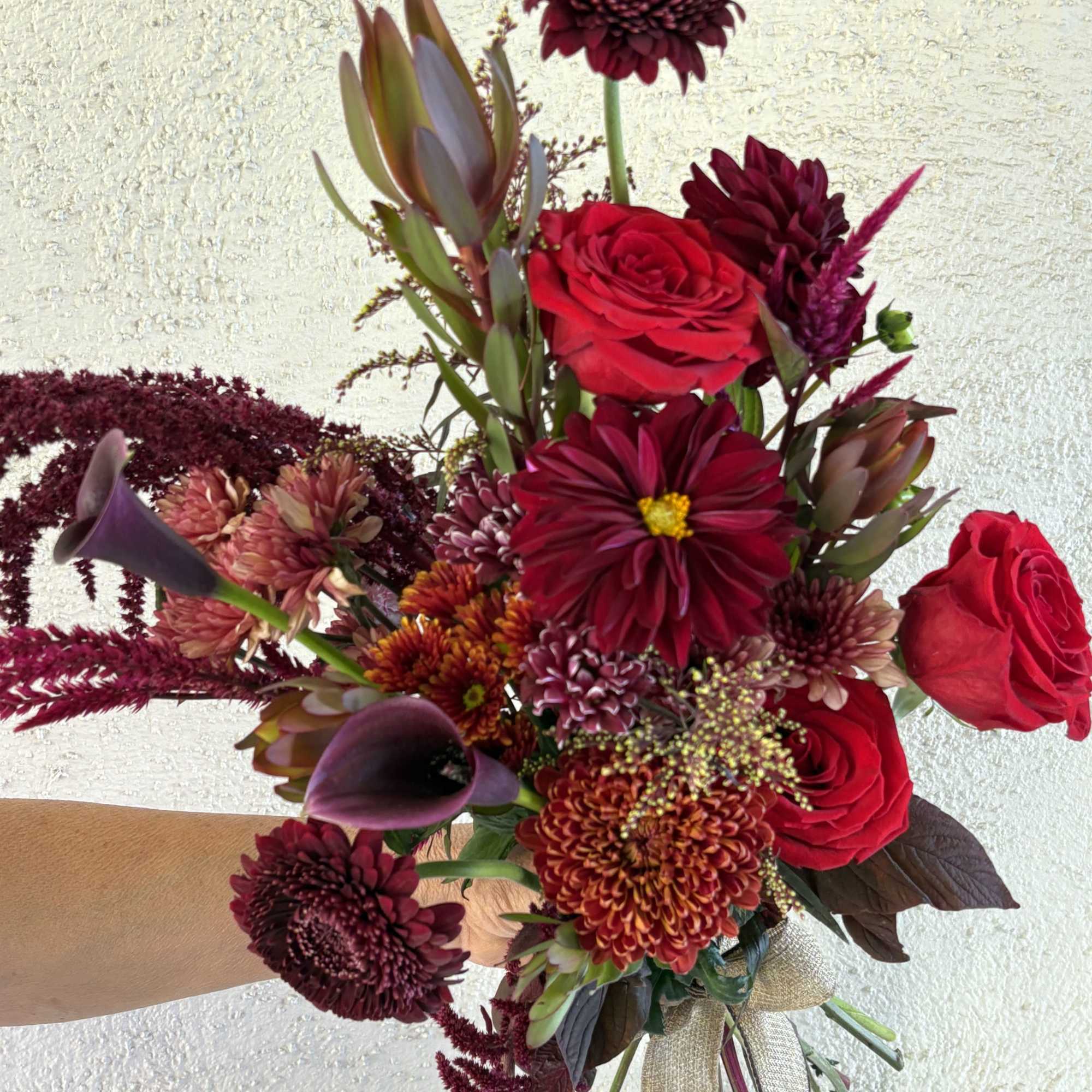 Handheld bouquet of red roses, burgundy chrysanthemums, and purple calla lilies