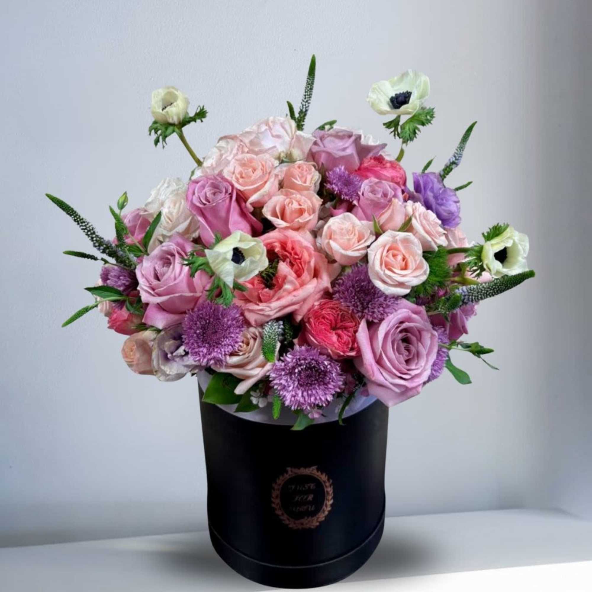 Pink and lavender roses with purple blooms in a black hatbox, photo 2 of 2