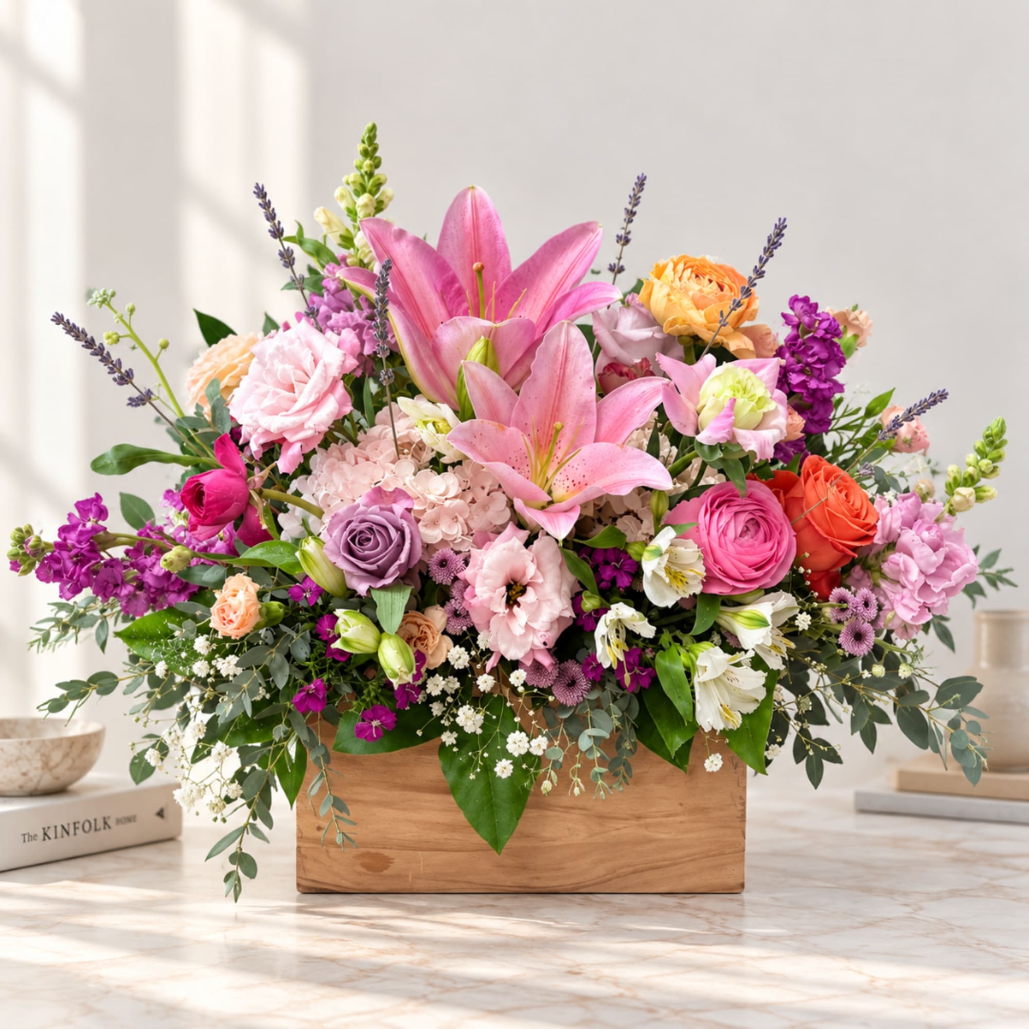 Mixed bouquet with pink lilies, roses, and purple flowers in a wooden box