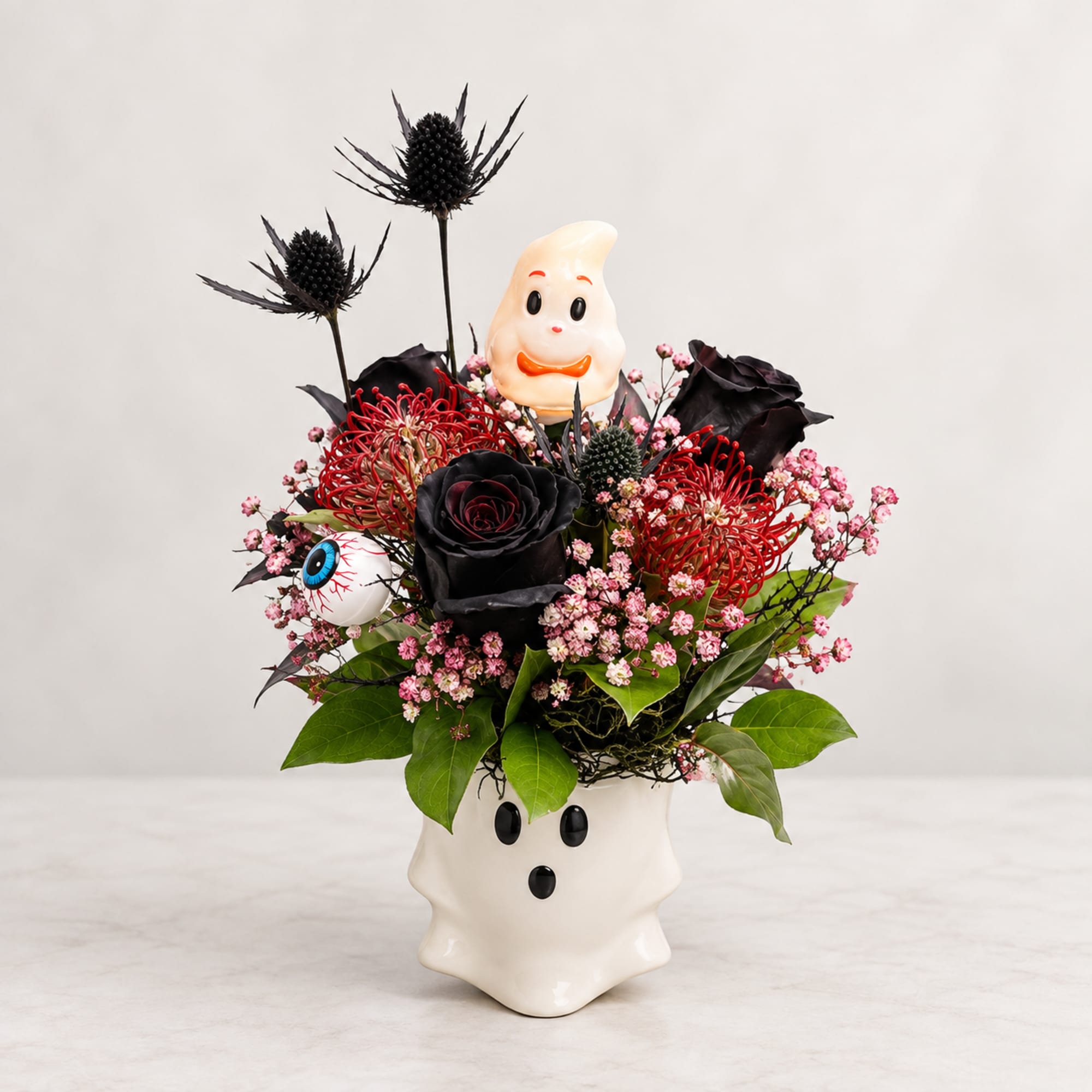 Halloween floral arrangement in a ghost-shaped vase with black and red flowers