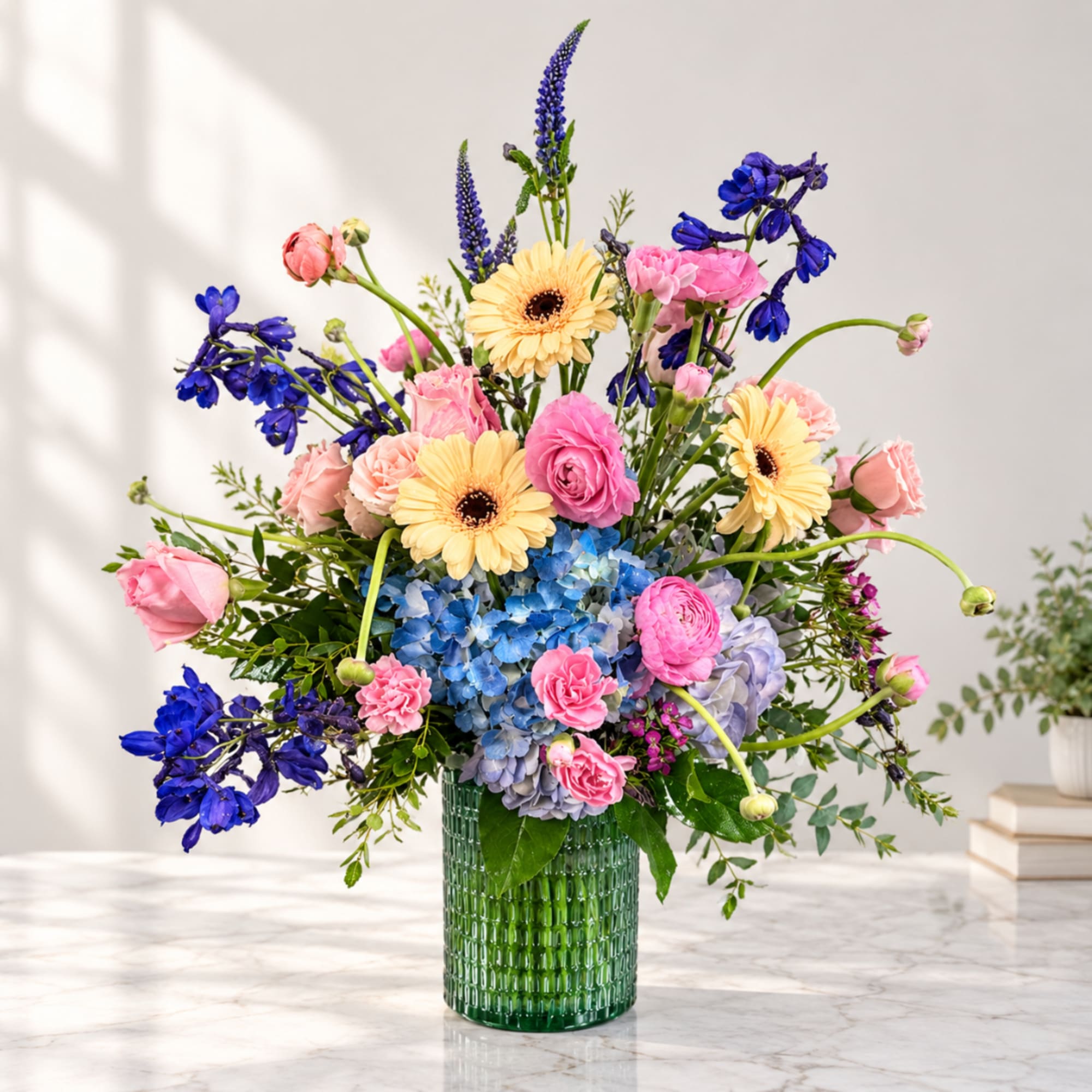 Colorful mixed bouquet in a green glass vase with pink, yellow, blue, and purple blooms