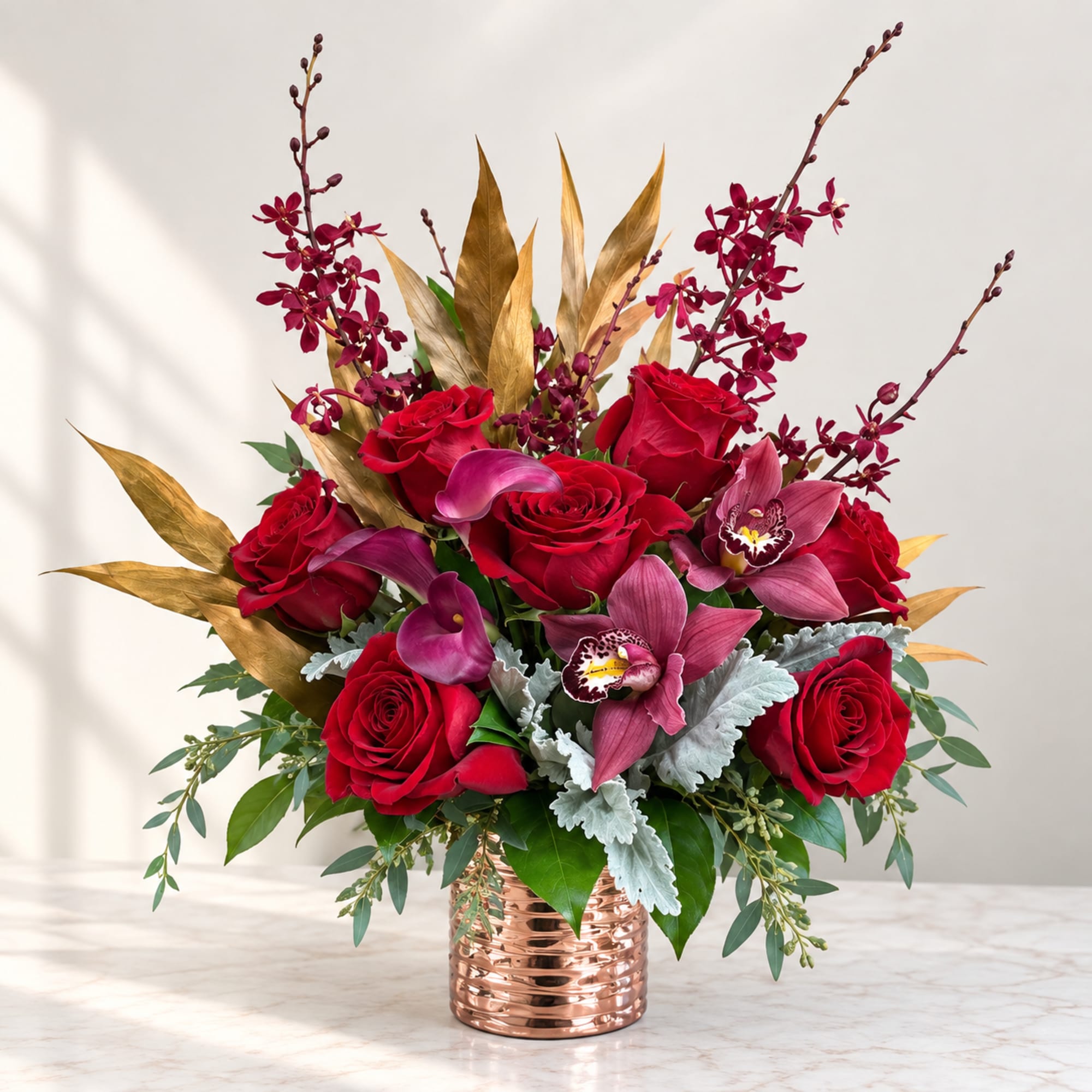 Red roses and pink orchids arranged in a copper vase