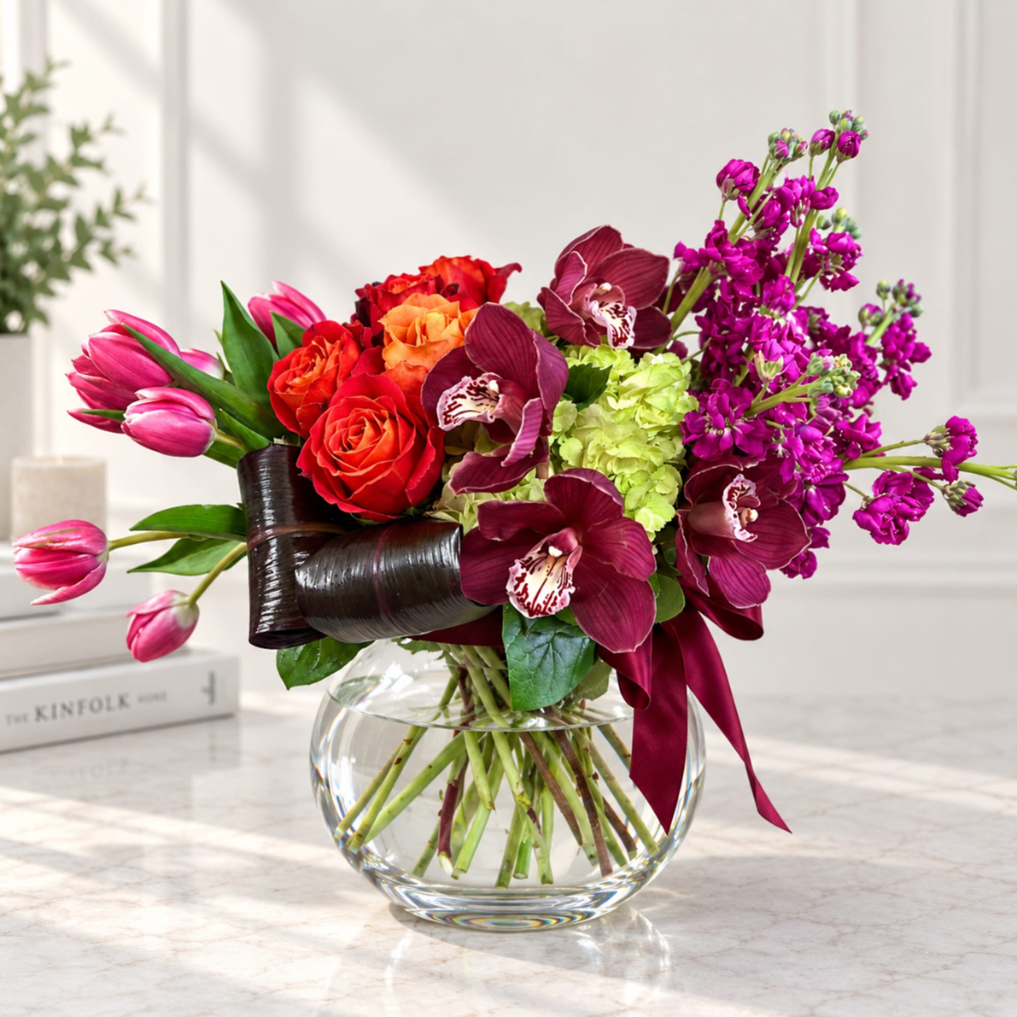 Mixed bouquet of roses, orchids, tulips, and hydrangea in a glass vase