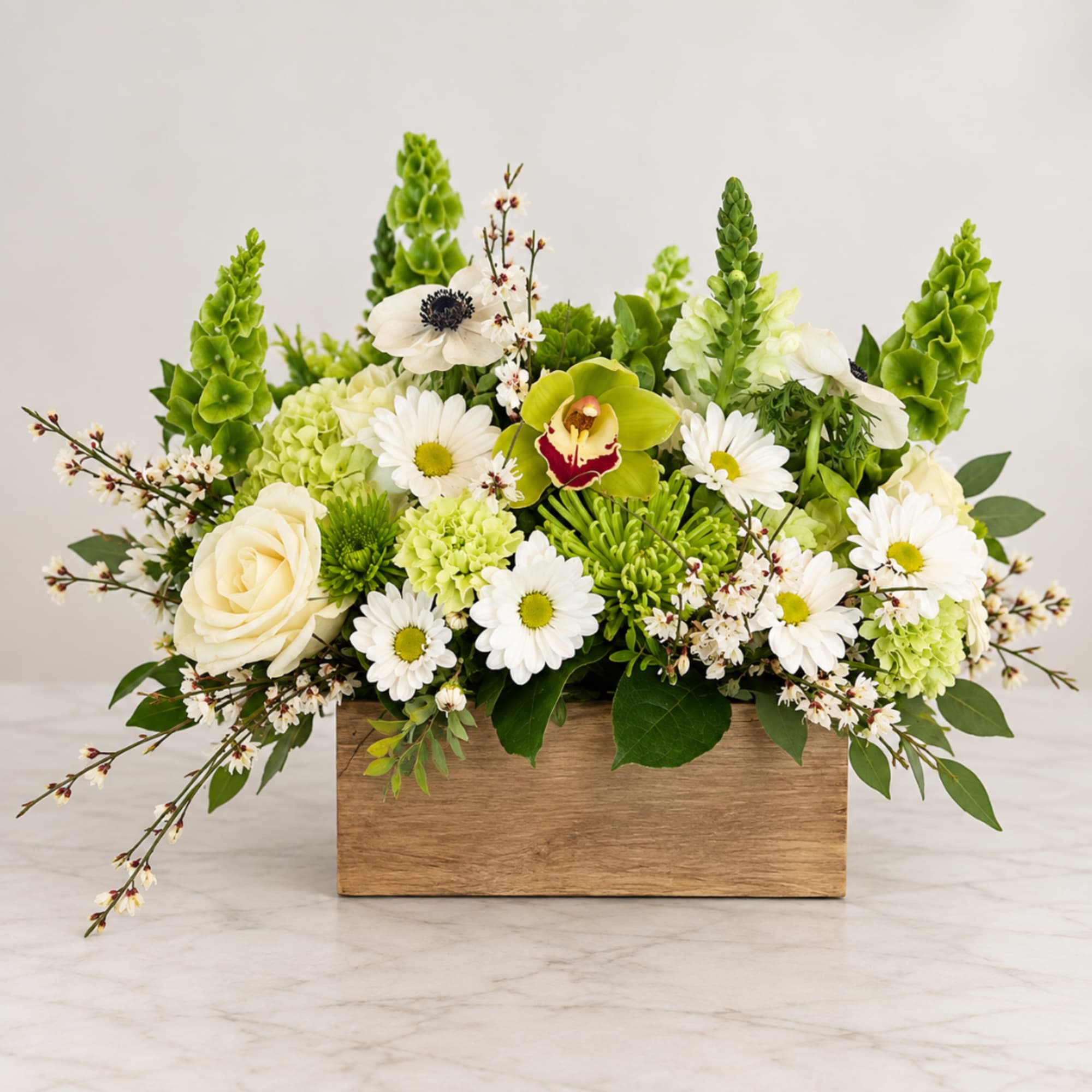 White and green floral arrangement in a wooden box