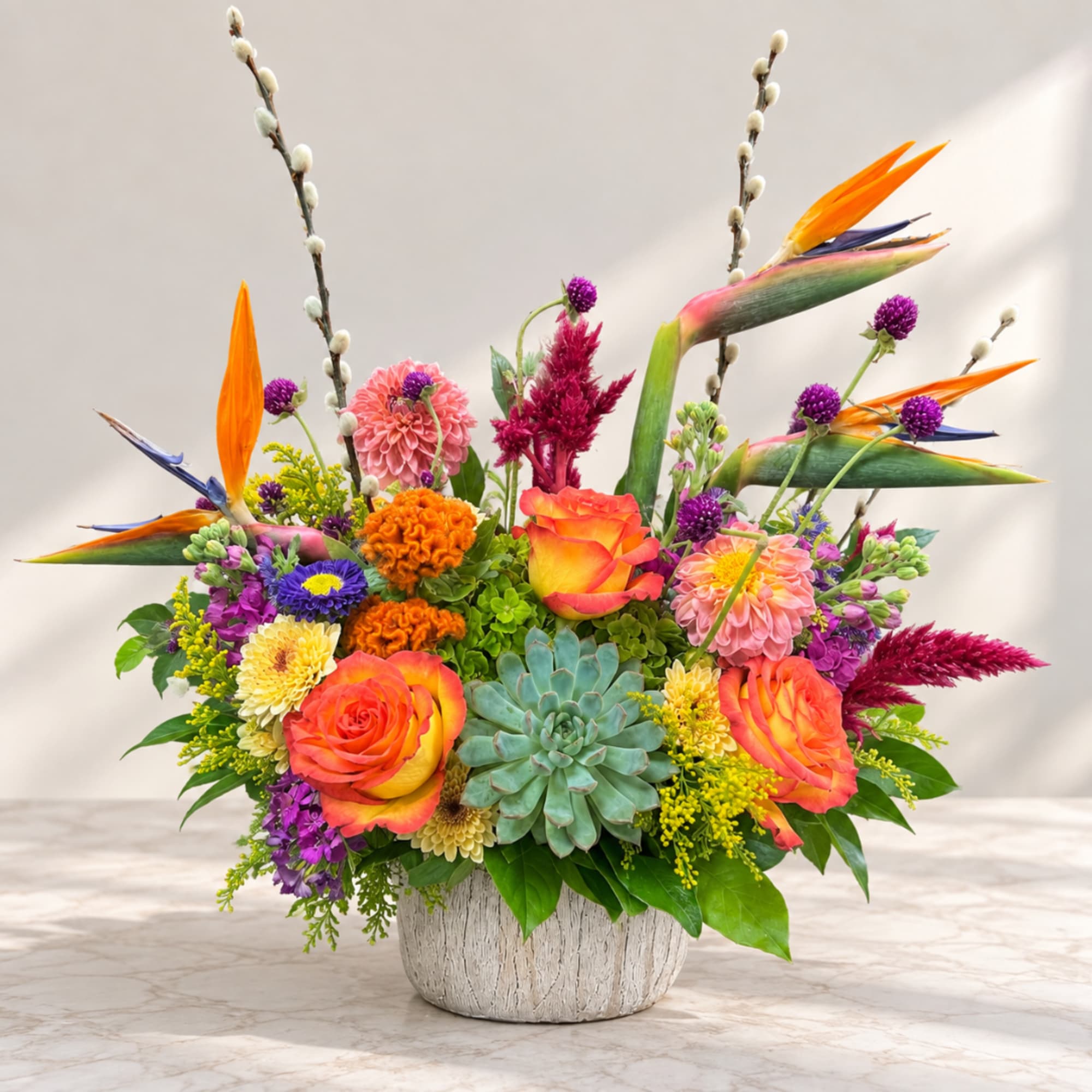Colorful mixed flower arrangement in a white textured pot with a succulent centerpiece