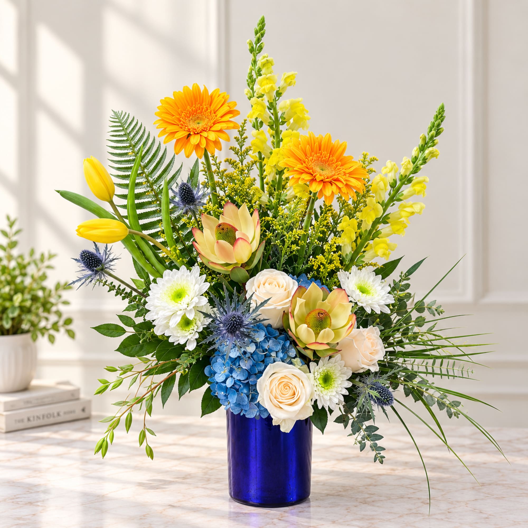 Bright mixed bouquet in a blue vase with yellow, white, and blue flowers