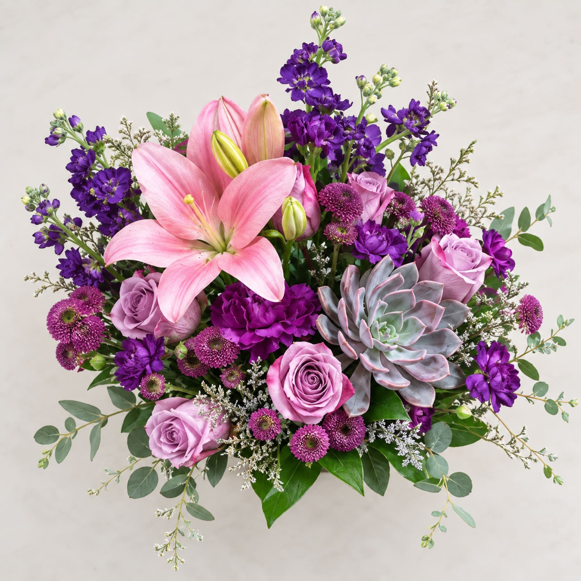 Pink lilies and lavender roses with purple blooms in a bouquet