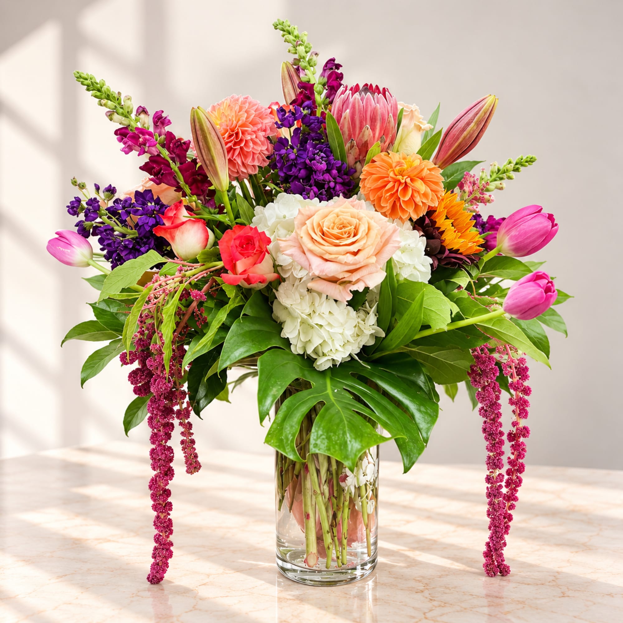 Mixed bouquet of pink, peach, purple, and orange flowers in a glass vase