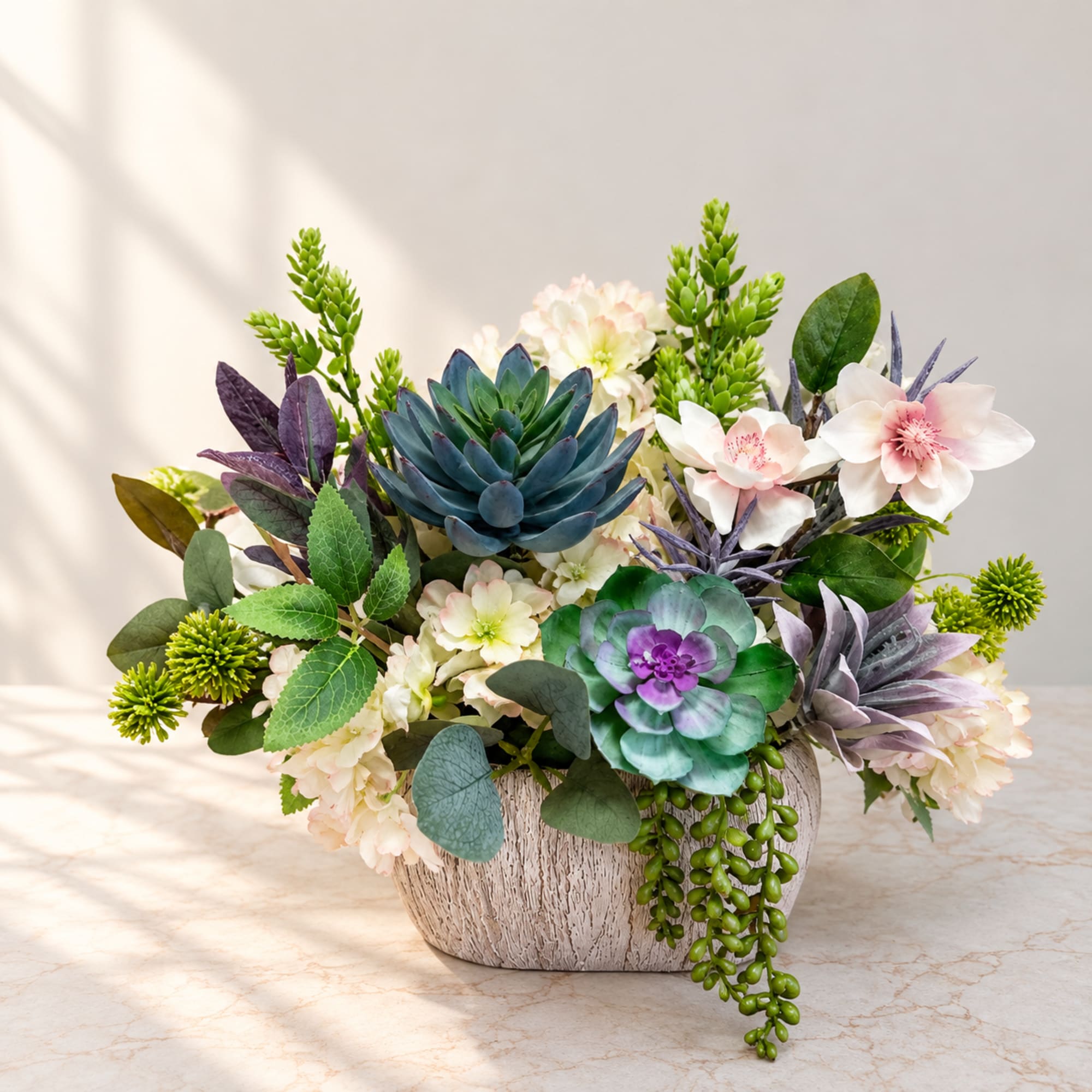 Mixed floral arrangement in a textured white vase with succulent accents