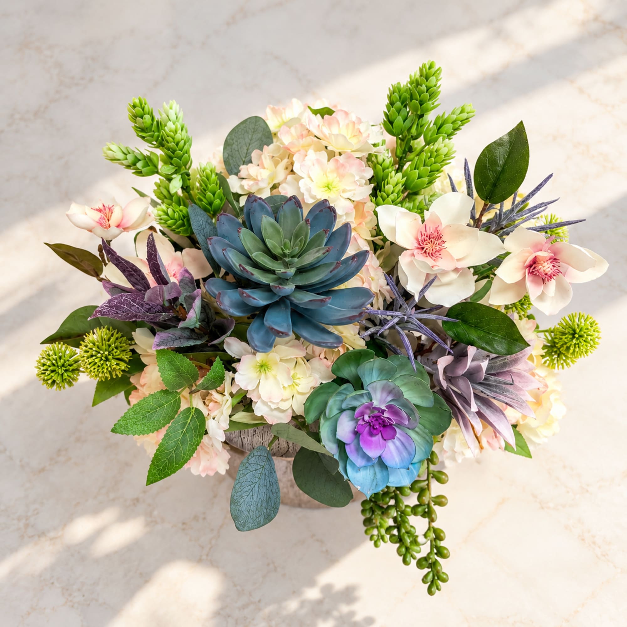 Succulent arrangement with pale pink flowers in a low container