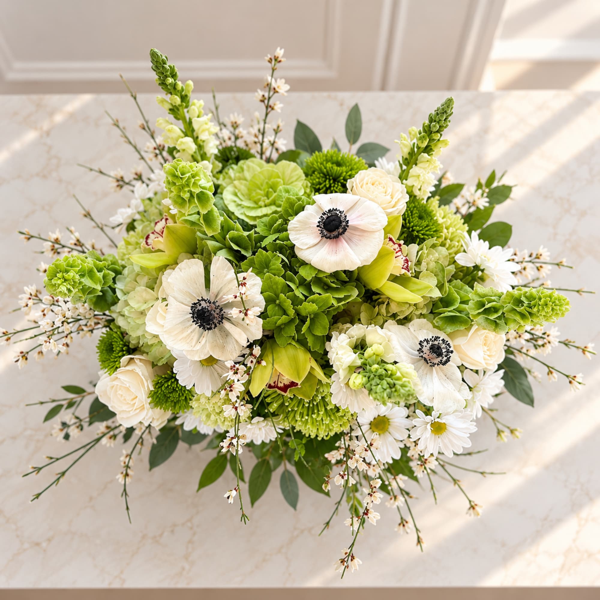 Green and white floral arrangement with anemones and roses