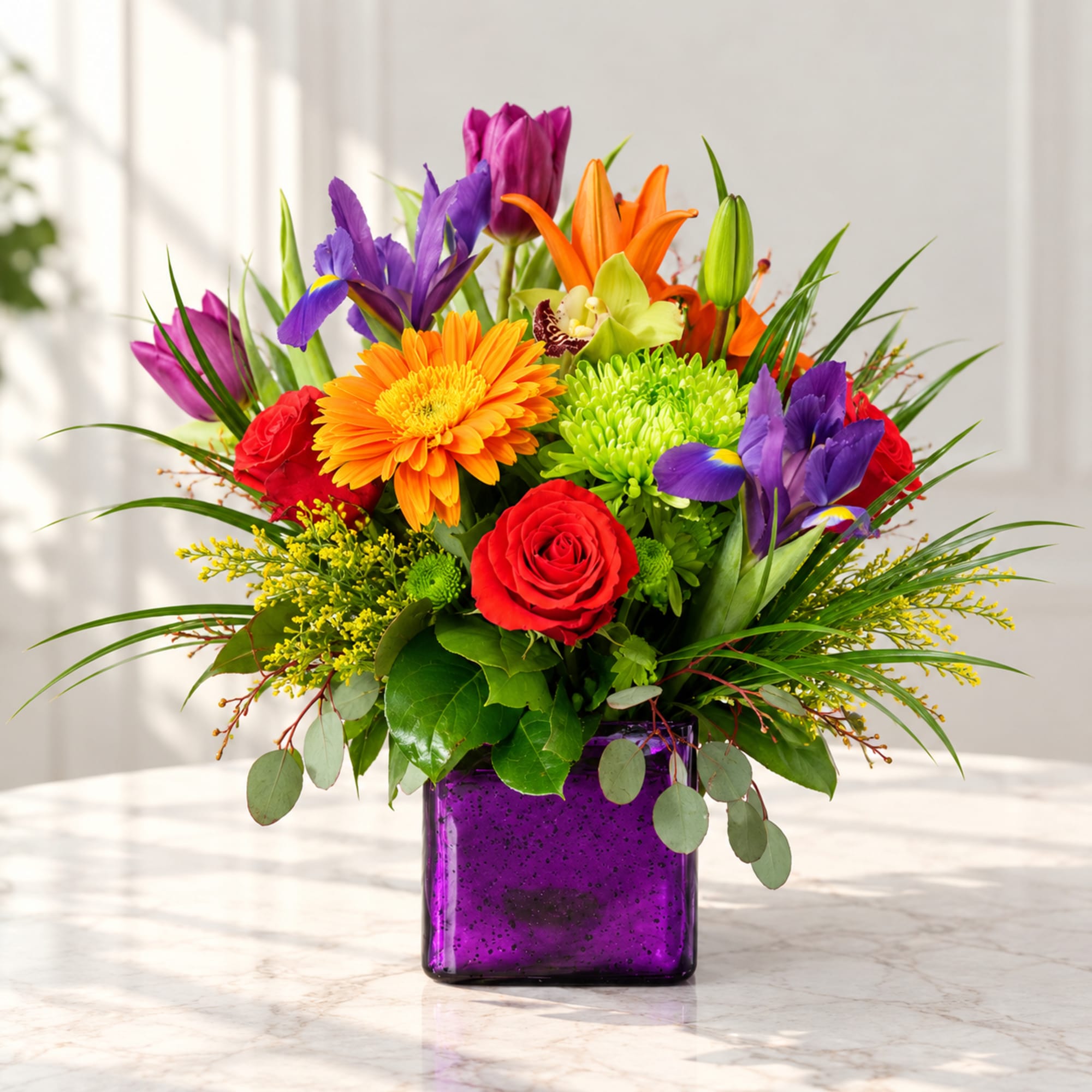 Colorful bouquet of roses, lilies, irises, and chrysanthemums in a purple vase