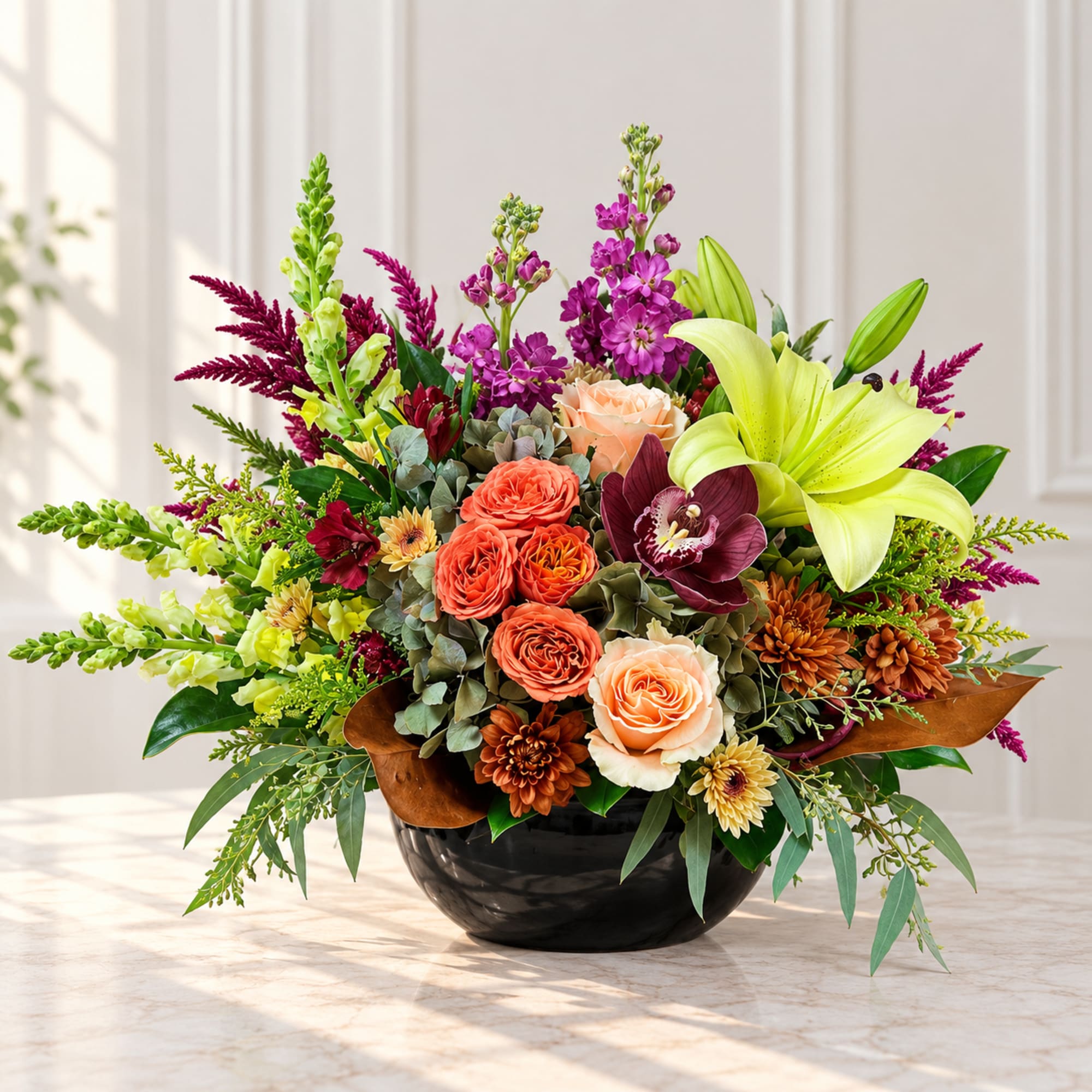 Mixed bouquet in a black bowl vase with lilies, roses, orchids, and snapdragons