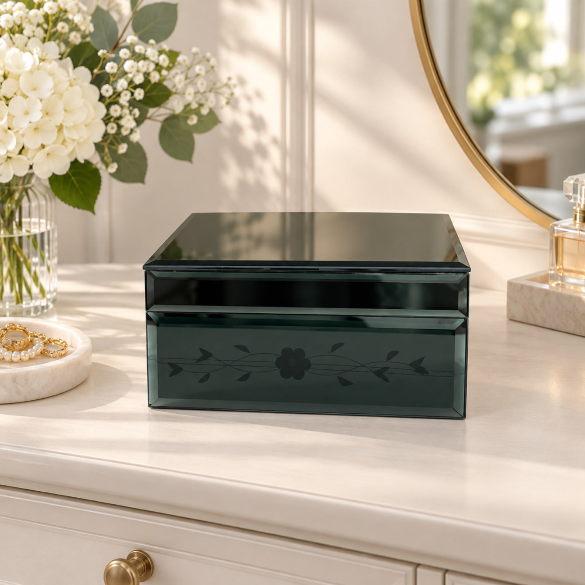 Dark glass keepsake box on a dresser beside a white floral arrangement