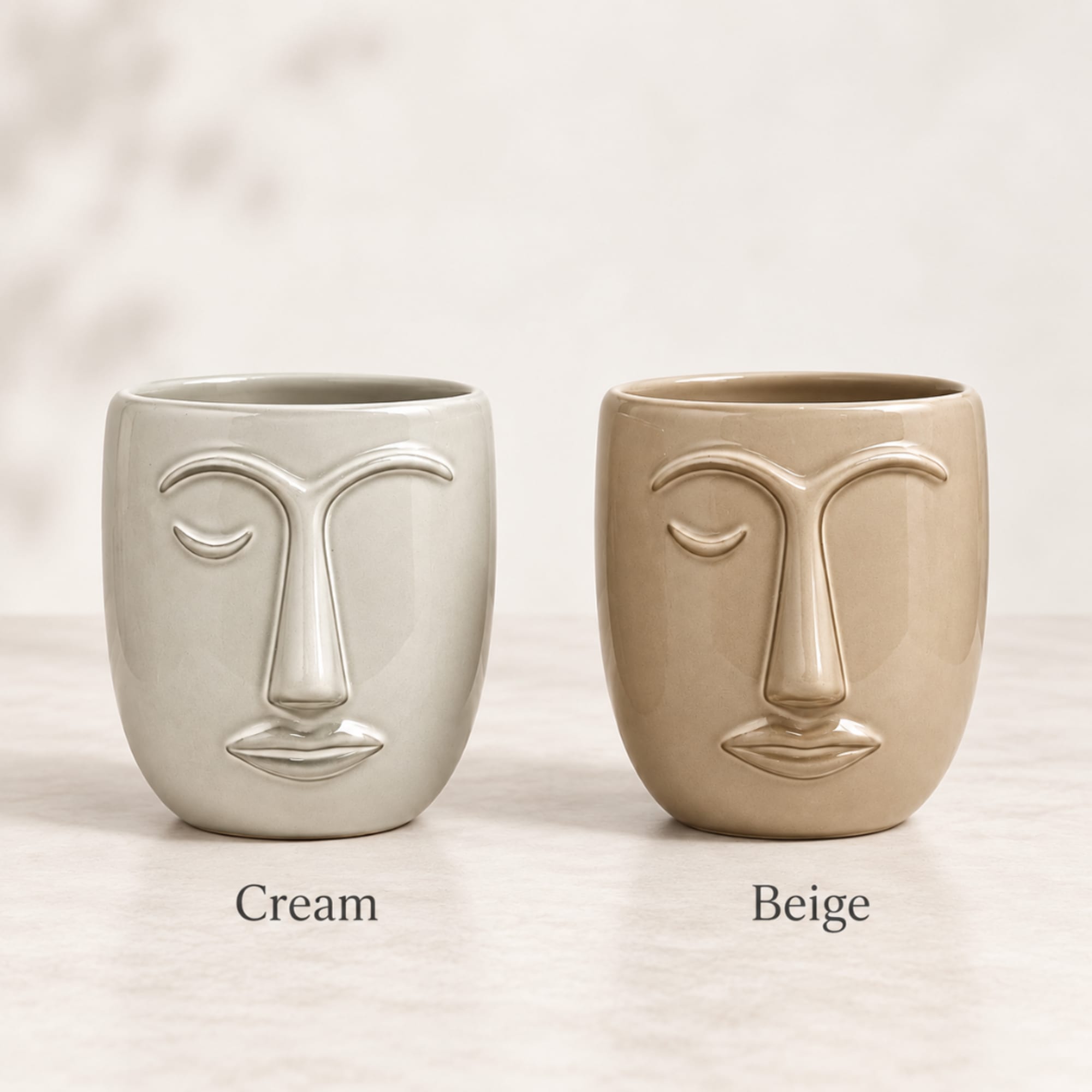 Two face-shaped ceramic planters in cream and beige