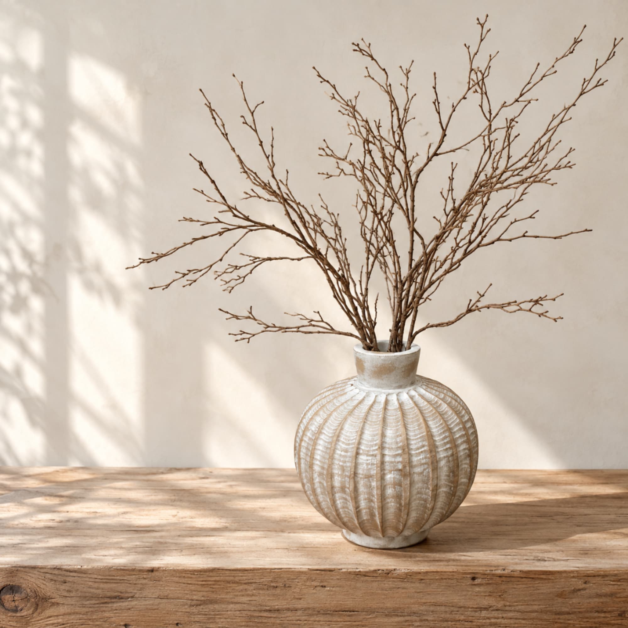 Decorative vase with bare branches on a wooden table